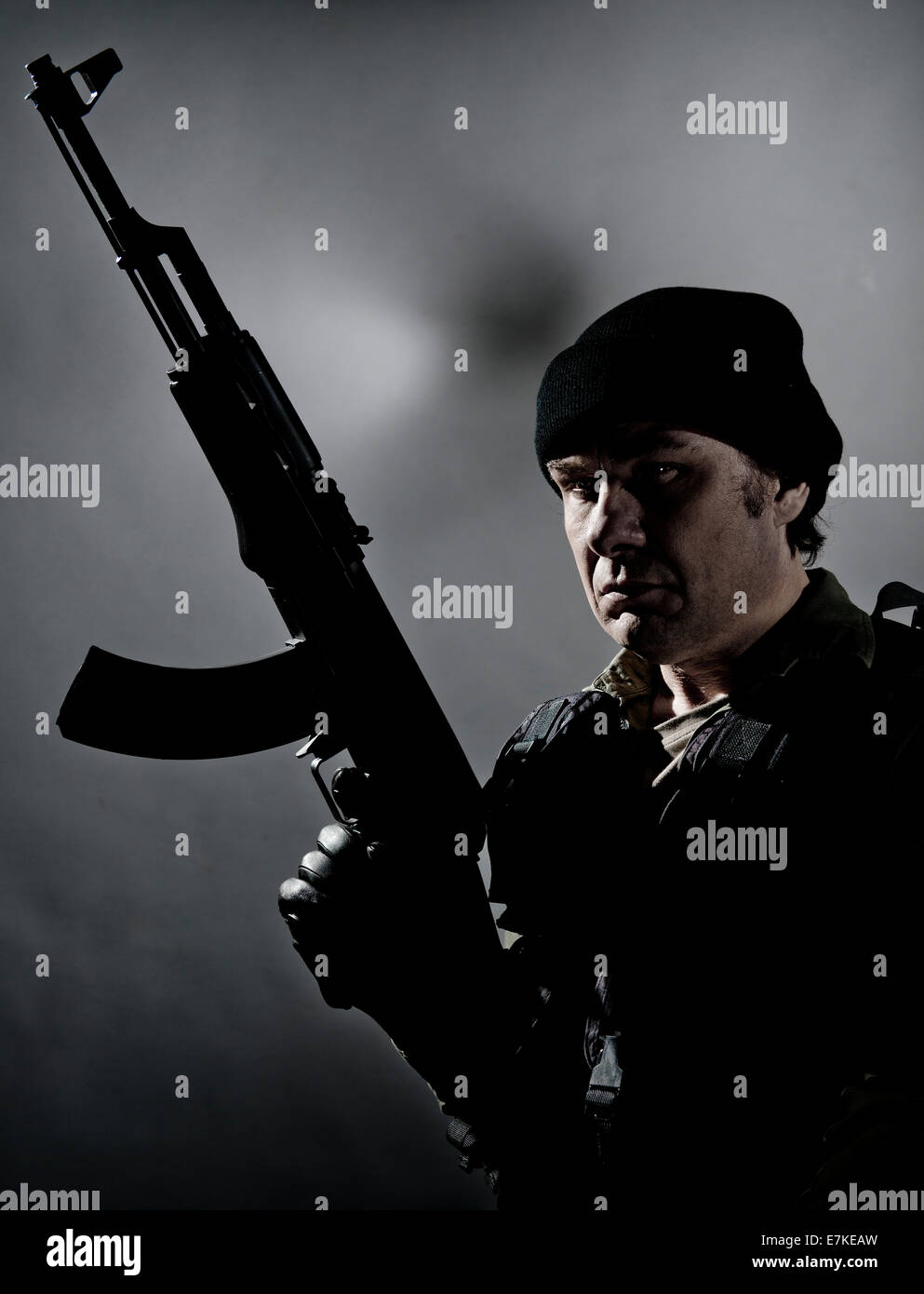 Meine allgemeine bewaffnete Kämpfer, hält eine AK-47 Gewehr, teilweise vor einem grauen Hintergrund abhebt. Stockfoto