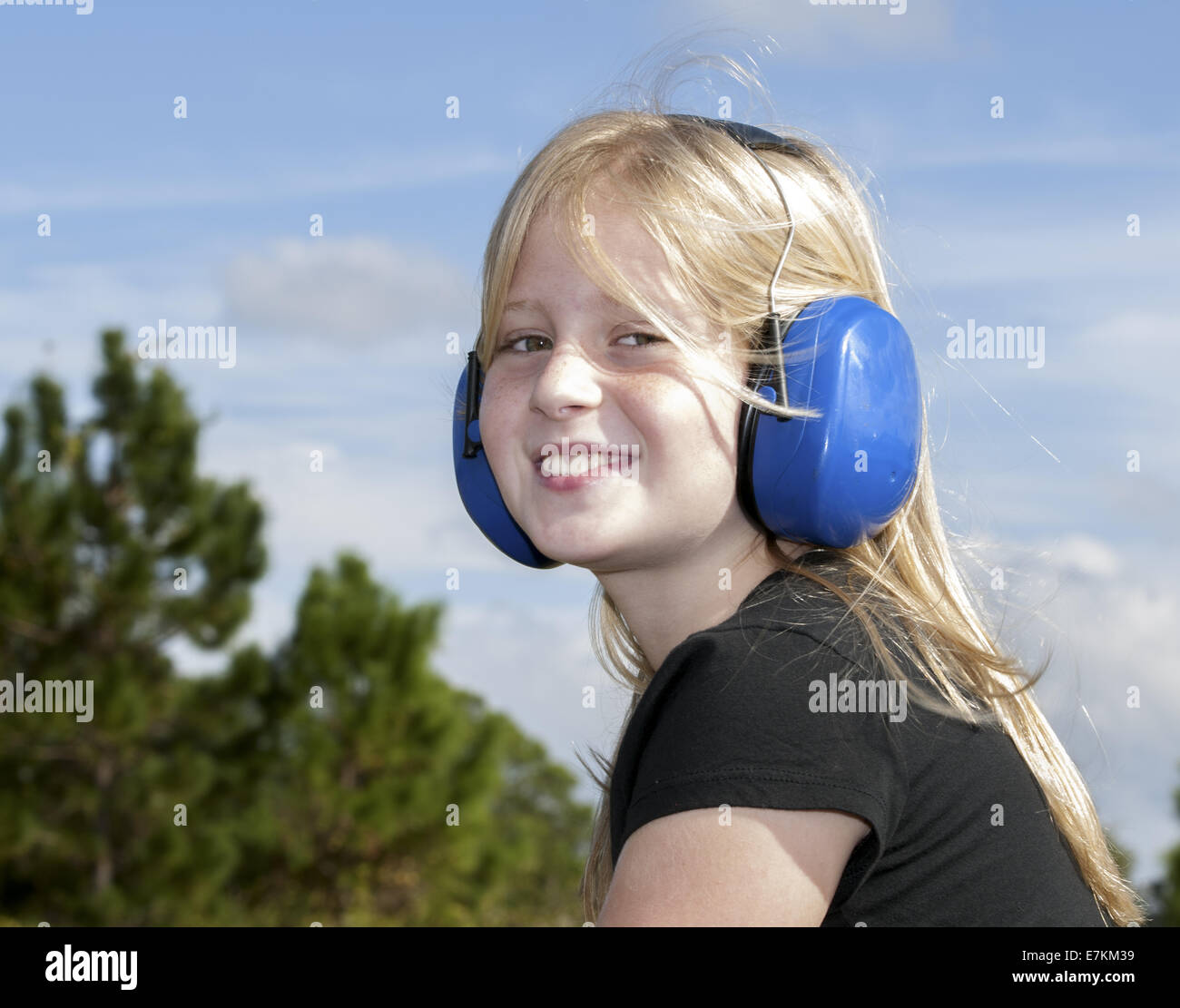 8-9 Jahre altes Mädchen mit blauen Gehörschutz Stockfoto