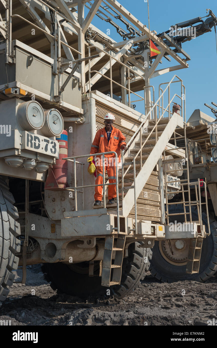 Ein müden Muldenkipper Operator klettert auf der Vorderseite seines Trucks am Ende einer Schicht in einem Tagebau afrikanischen Kupfer mine. Stockfoto