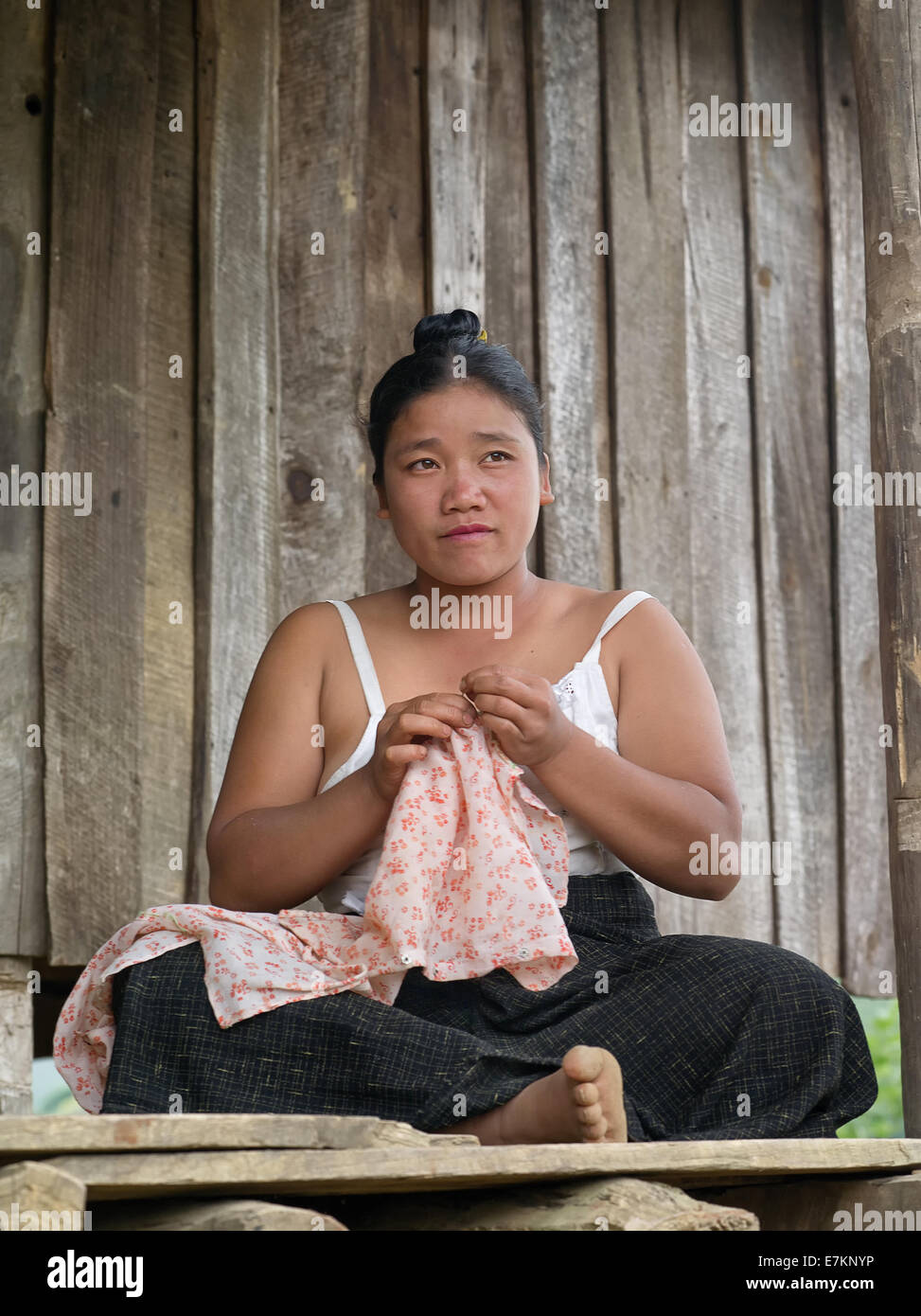 Burmesische Frau an der Schwelle des Hauses engagiert beim Nähen. Stockfoto