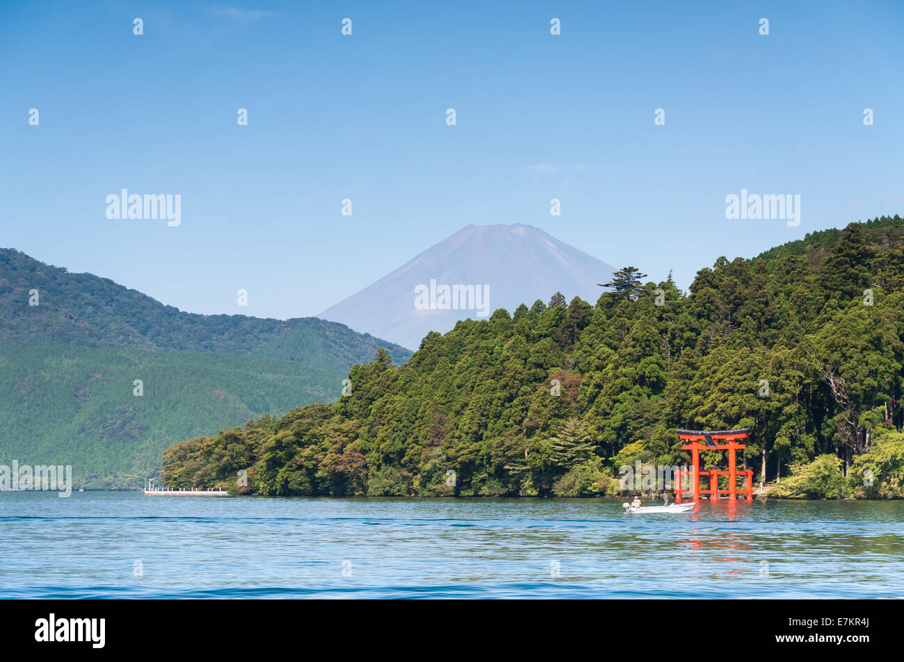 Ein rotes Torii-Tor steht am Ufer des See Ashi mit Mount Fuji in der Ferne. Stockfoto