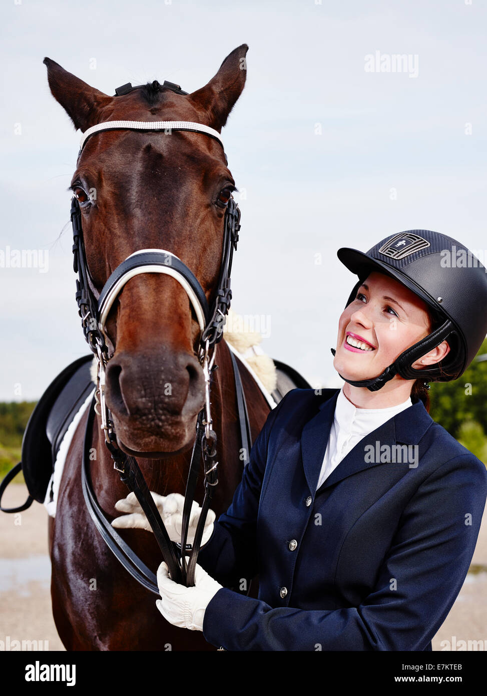 Braune Pferd und schöne Frau mit Pferd-Reiten-Bekleidung Stockfoto