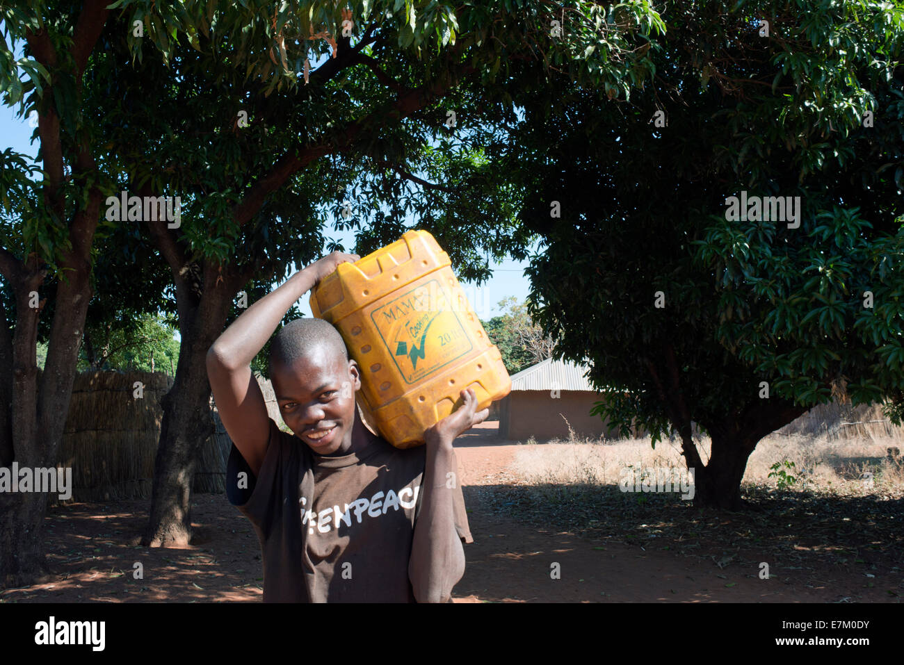 Einer der Bewohner des Mukuni Village bringt eine Wasser-Jerican. Er trägt ein T-shirt von Greenpeace. Mukuni Village – ein einzigartiges Stockfoto