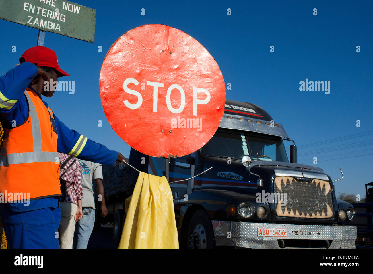 Eine Frau steuert den Datenverkehr zwischen Sambia und Simbabwe.  Ein STOP-Schild zeigt, dass wir Sambia eintreten. Heute eines der V Stockfoto