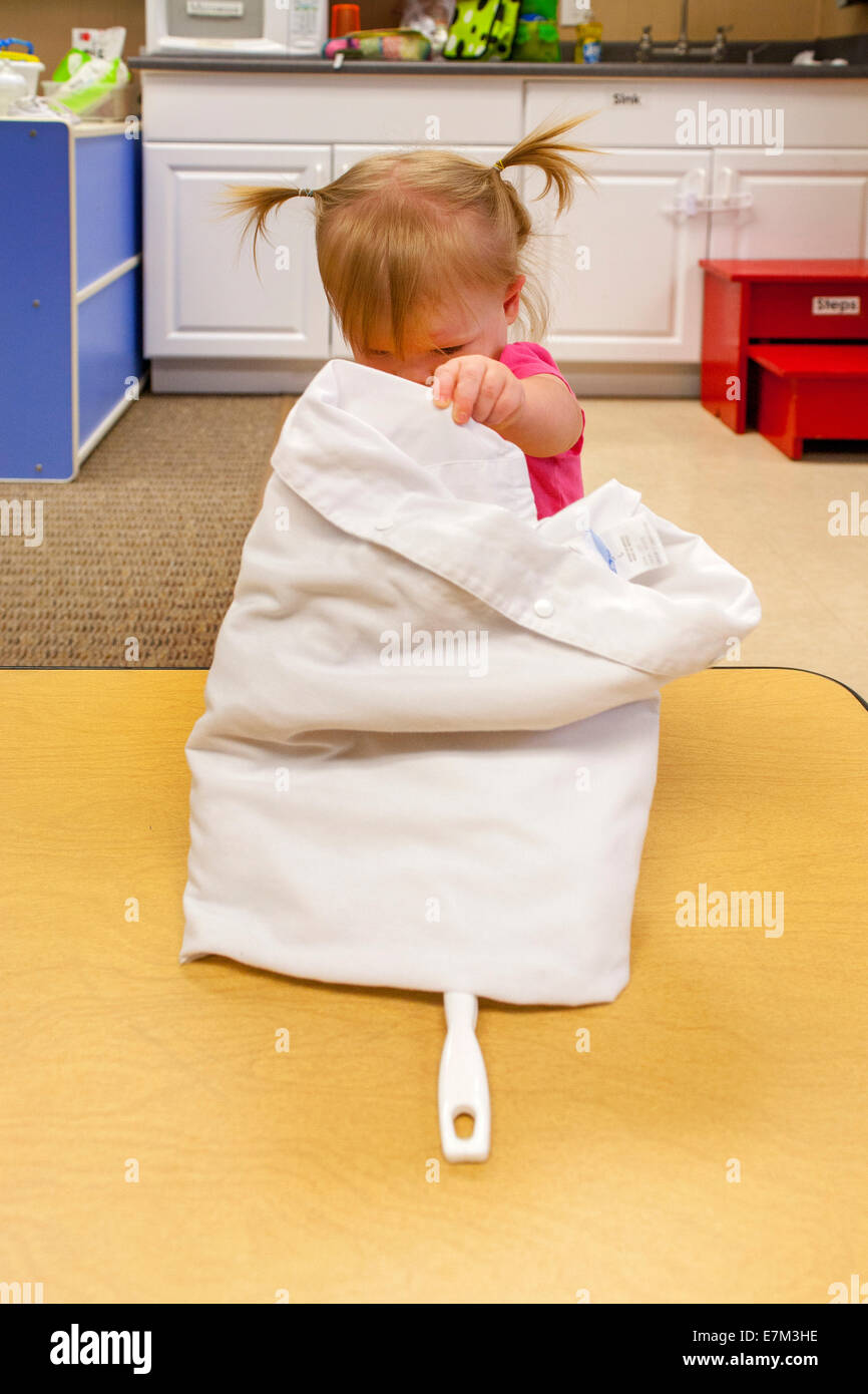 Mit Neugier, erreicht ein Mädchen unter einem Tuch, eine Spielzeug an einer Kindertagesstätte in Tustin, Kalifornien zu finden. Stockfoto
