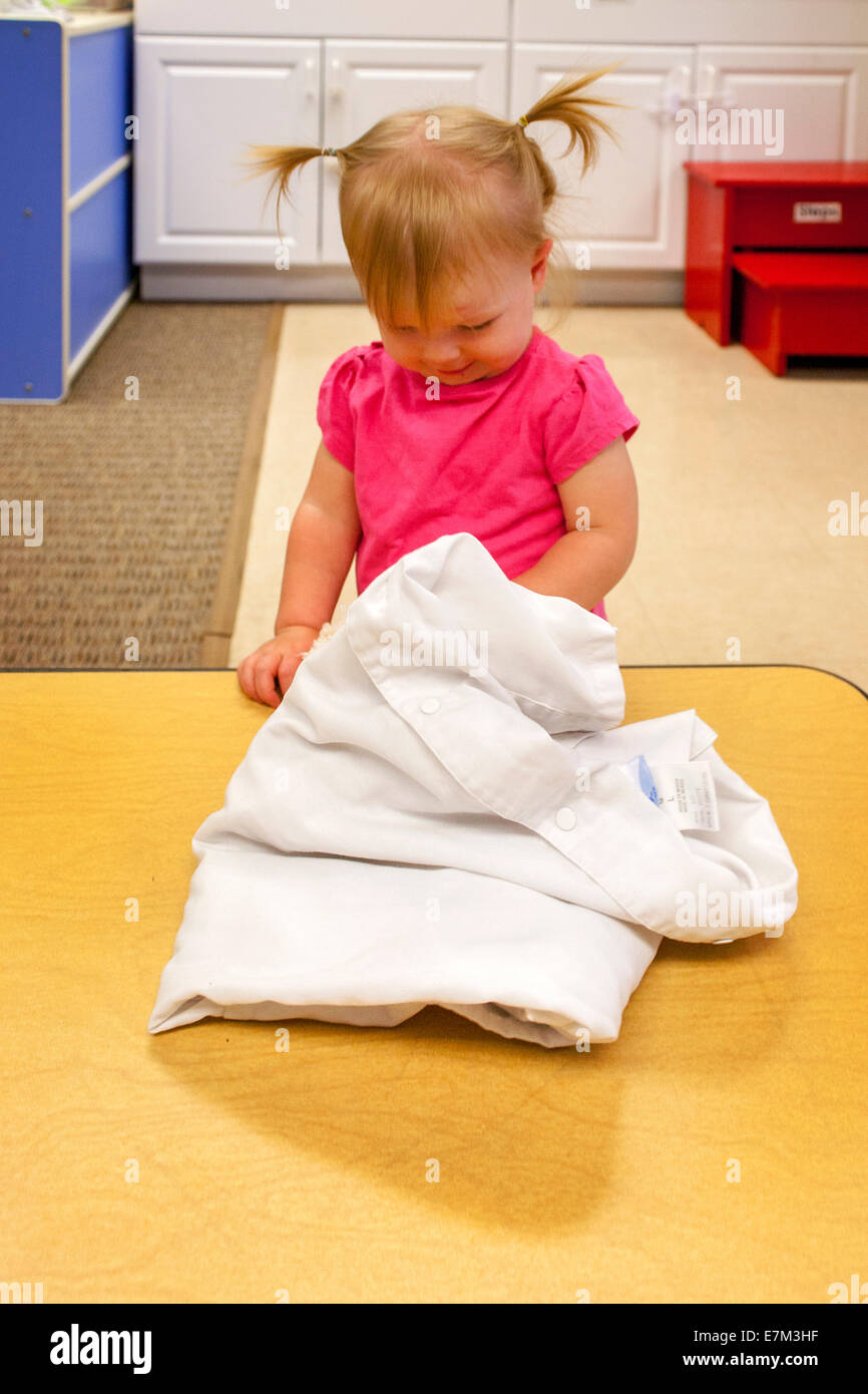 Mit Neugier, erreicht ein Mädchen unter einem Tuch, eine Spielzeug an einer Kindertagesstätte in Tustin, Kalifornien zu finden. Stockfoto