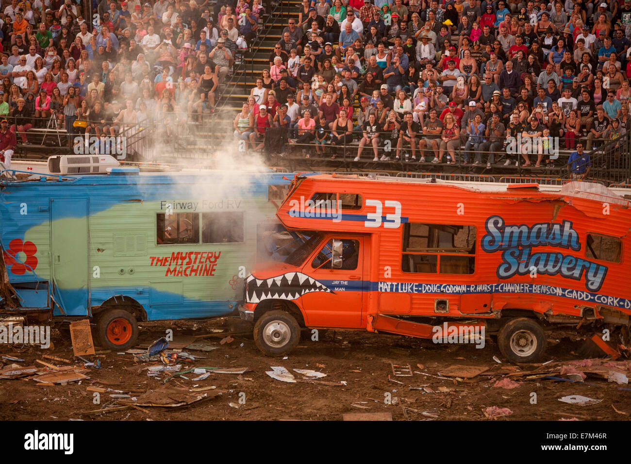 Dampf steigt von Heizkörper wie bunt bemalte Reisemobile Absturz zusammen in einem Demolition Derby in der Abenddämmerung im Orange County Fair in Costa Mesa, Kalifornien. Das Objekt des Derby ist für die Fahrzeuge sich gegenseitig zu zerstören. Beachten Sie die Zuschauer im Hintergrund. Stockfoto