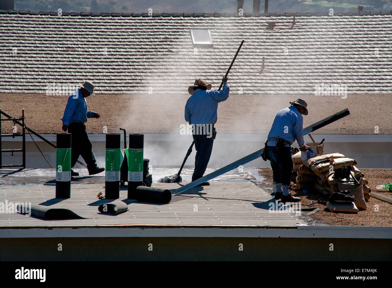 Dampf steigt aus heißem Teer als Hispanic Arbeiter ersetzen ein Garagendach in Laguna Niguel, CA. Hinweis Rollen Dachpappe. Stockfoto