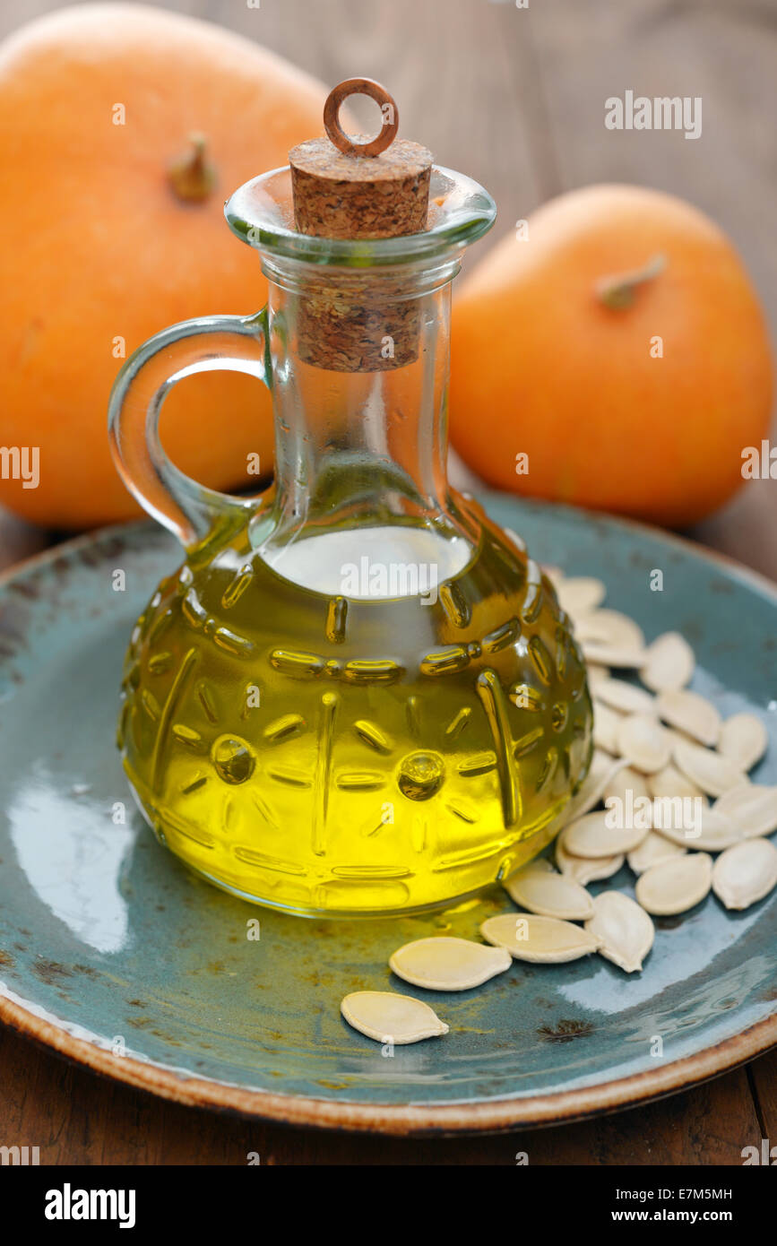Steirisches Kürbiskernöl in Flasche mit Samen und Kürbis auf hölzernen Hintergrund Stockfoto