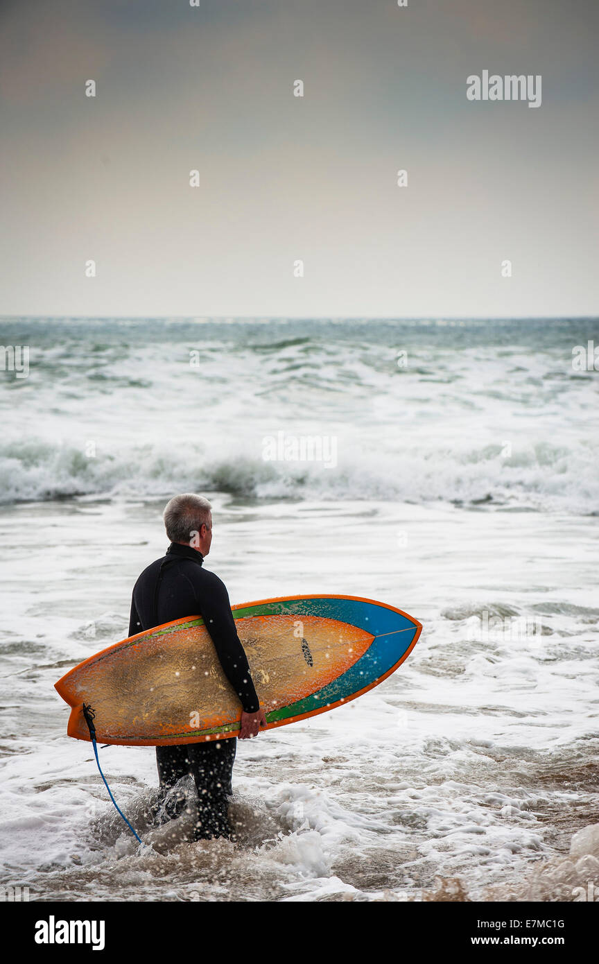 Ein Surfer, stehend in das Meer, die Wellen auschecken. Stockfoto