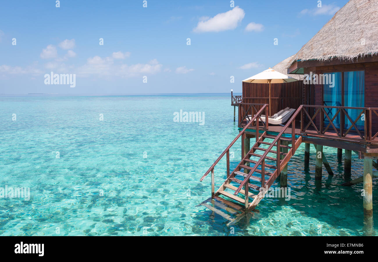 Türkisfarbene Lagune in einem tropischen Ozean, Teil der Überwasser-Bungalow mit Schritte ins Wasser. Stockfoto