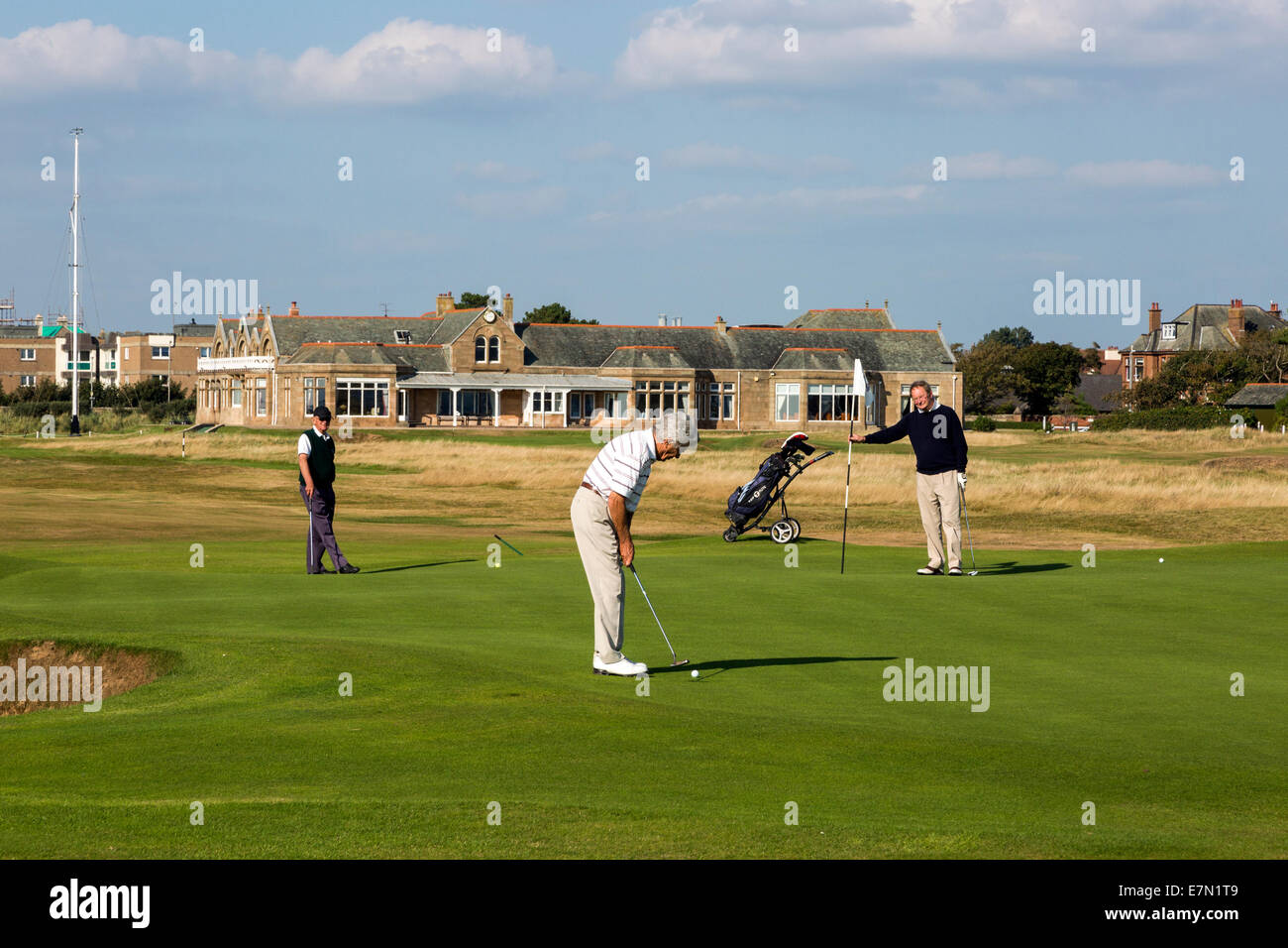 Golfspieler auf der ersten Grünen in Royal Troon Golf Club, Troon, Ayrshire, Schottland mit dem Klubhaus im Hintergrund Stockfoto