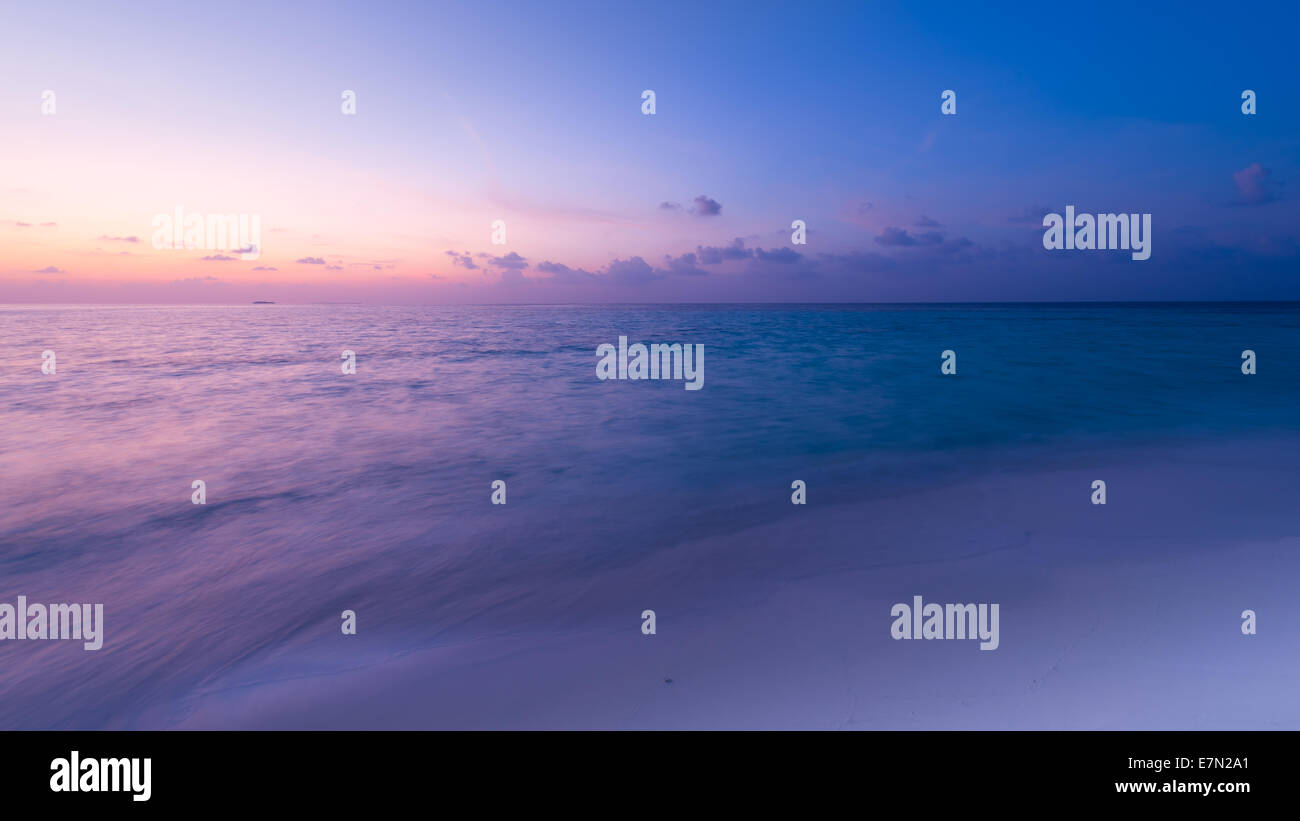 Herrlichen Sonnenuntergang über dem Ozean. Spritzen der Wellen auf den weißen Sandstrand. Panorama der tropischen Insel. Malediven Stockfoto