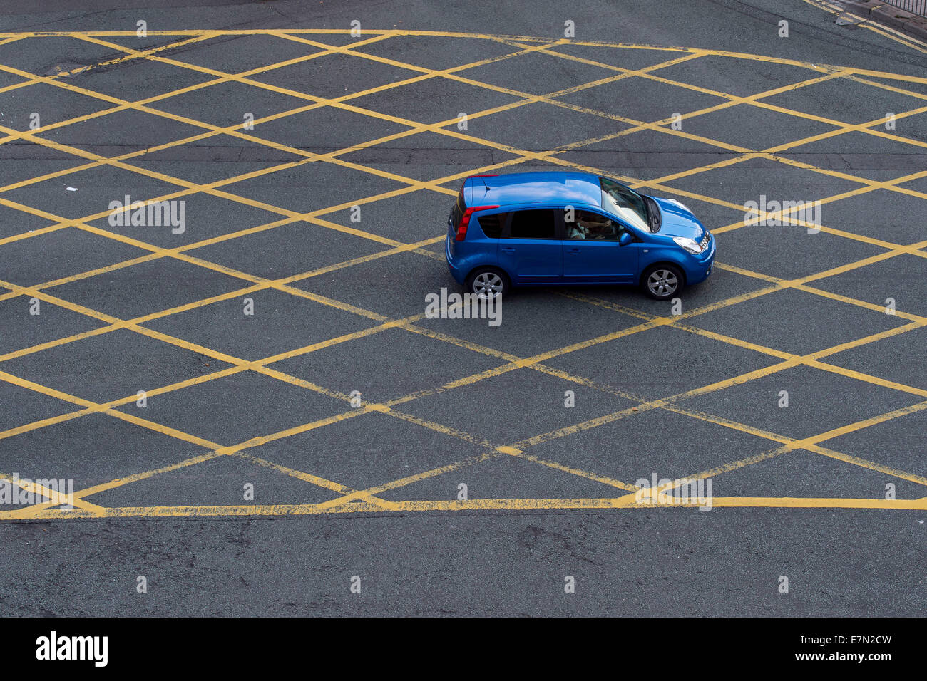 Ein blaues Auto fährt durch eine gelbe Box-Kreuzung. Stockfoto