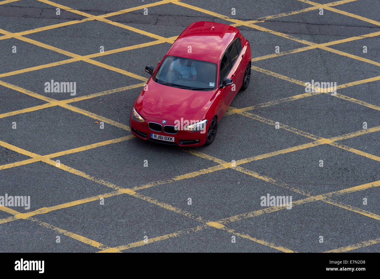 Ein rotes Auto in einer gelben Kasten-Kreuzung. Stockfoto