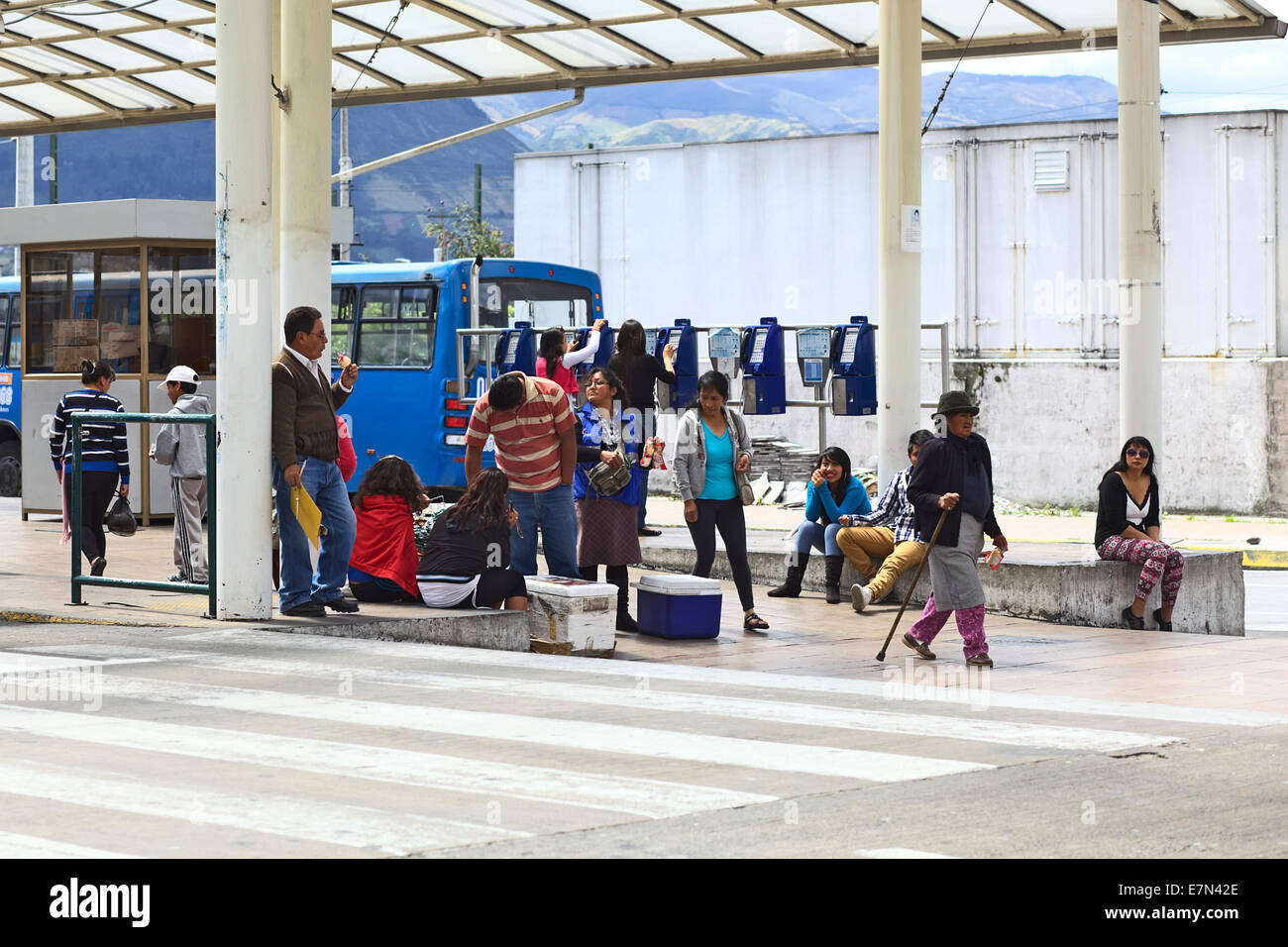 Nicht identifizierte Personen sitzen und gehen an der Bushaltestelle der lokalen Busse vor dem Quitumbe Terminal in Quito, Ecuador Stockfoto