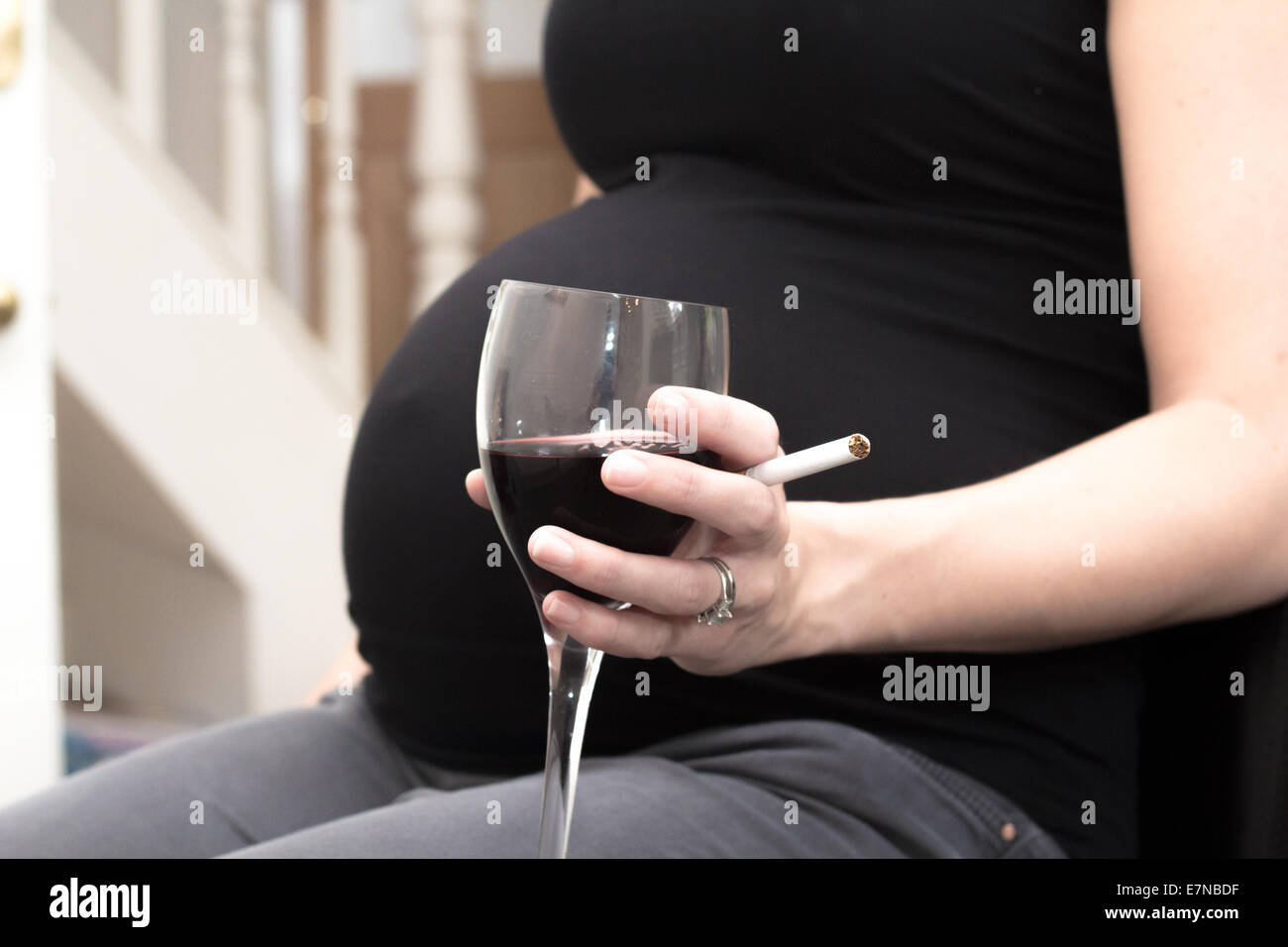 Schwangere Frau hält eine Zigarette und ein Glas Wein Stockfoto