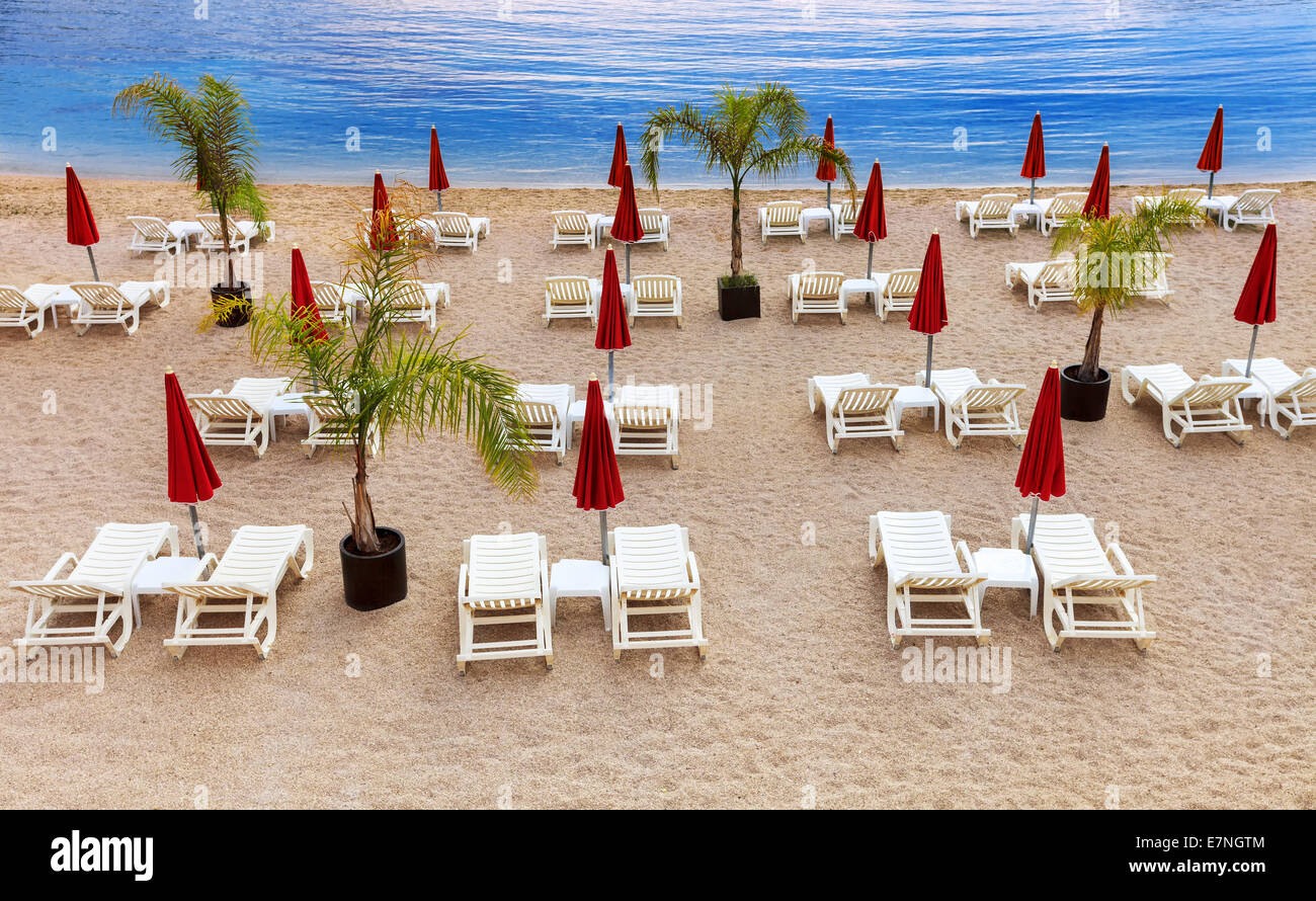 Strand am Mittelmeer mit weißen Sonnenliegen und rote Sonnenschirme Stockfoto