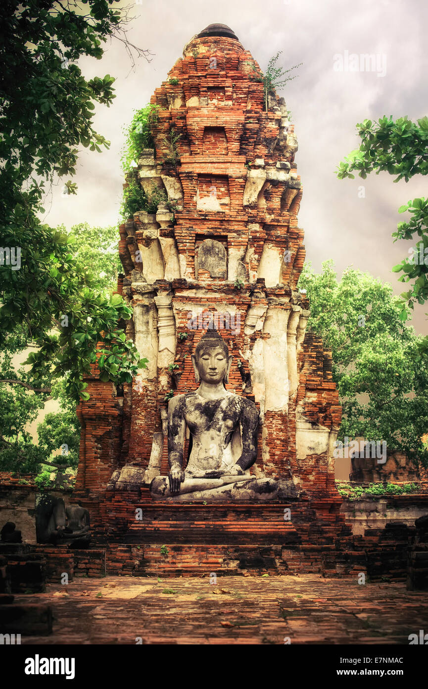 Asiatische Sakralarchitektur. Alten Sandstein Skulptur des Buddha im Wat Mahathat Ruinen unter Sonnenuntergang Himmel. Ayutthaya, Thailand Stockfoto