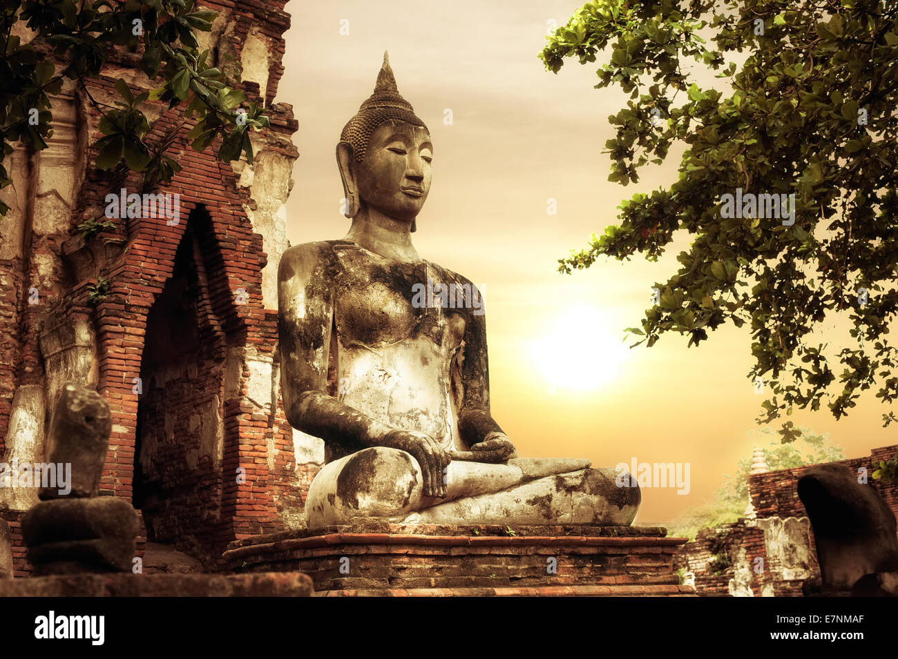 Asiatische Sakralarchitektur. Alten Sandstein Skulptur des Buddha im Wat Mahathat Ruinen unter Sonnenuntergang Himmel. Ayutthaya, Thailand Stockfoto