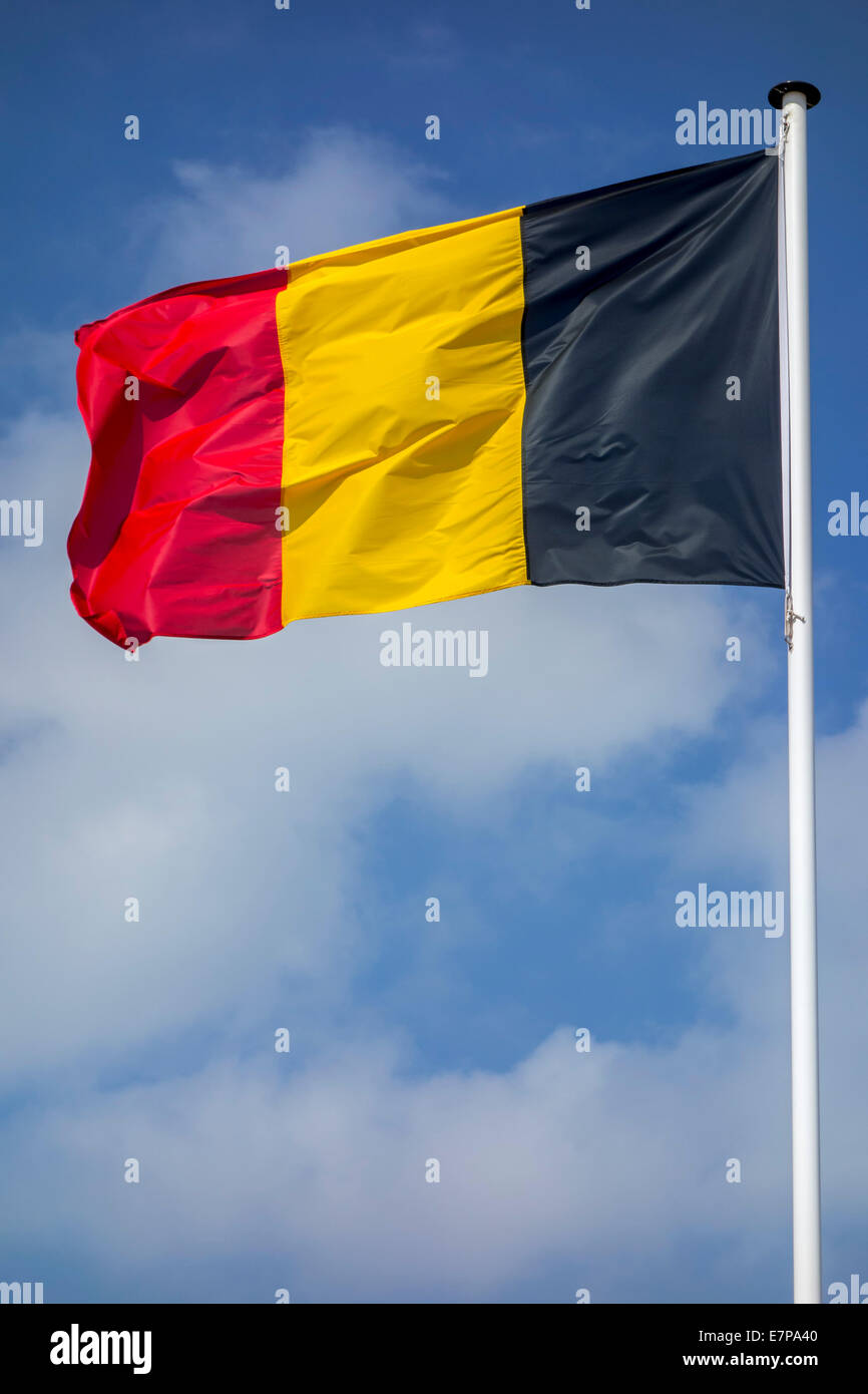 Belgische Nationalflagge Belgiens am Fahnenmast im Wind gegen bewölktem Himmel Stockfoto