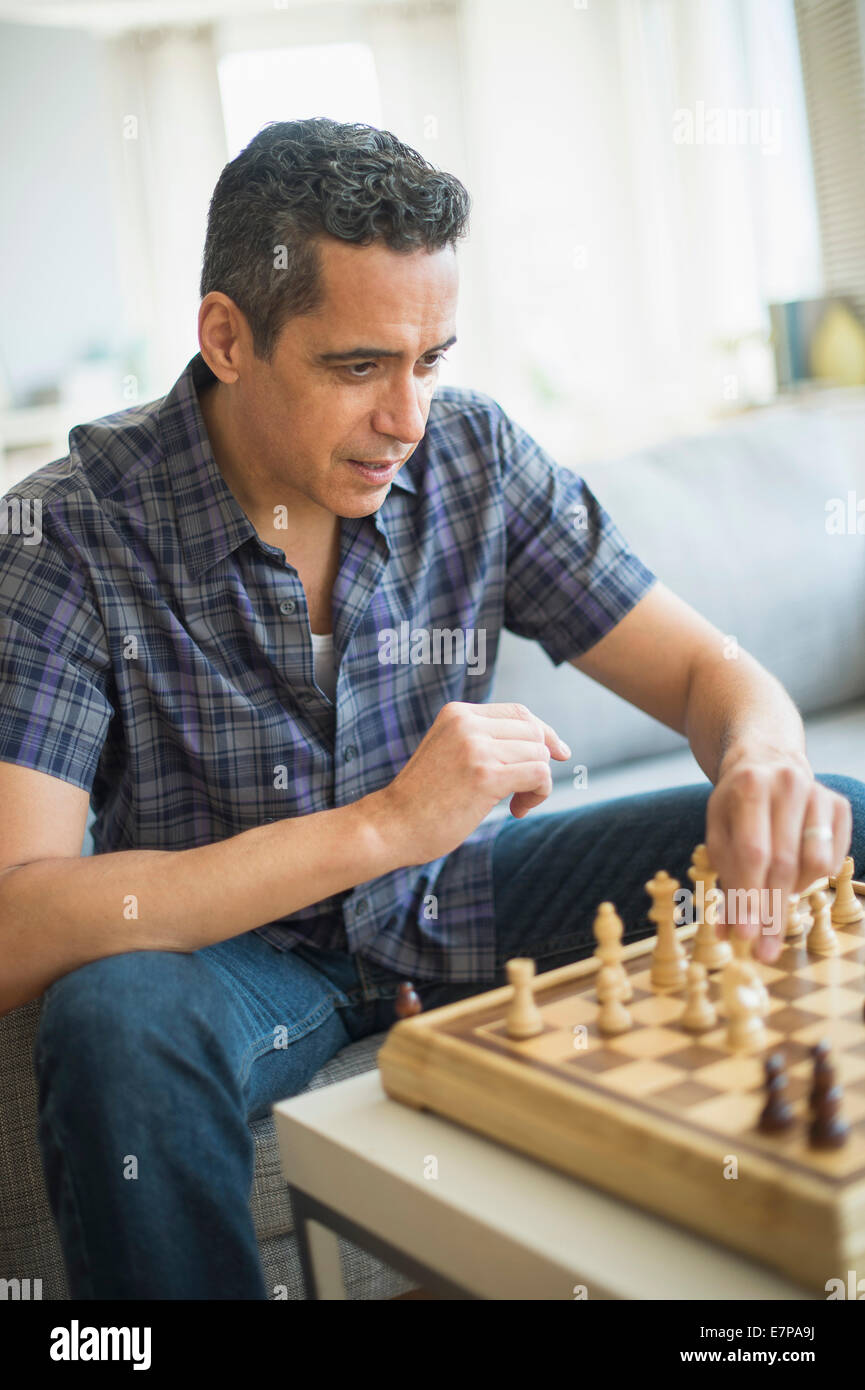 Mann spielt Schach im Wohnzimmer Stockfoto