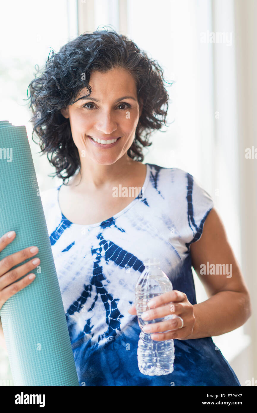 Portrait von lächelnden Frau mit Yoga-Matte Stockfoto