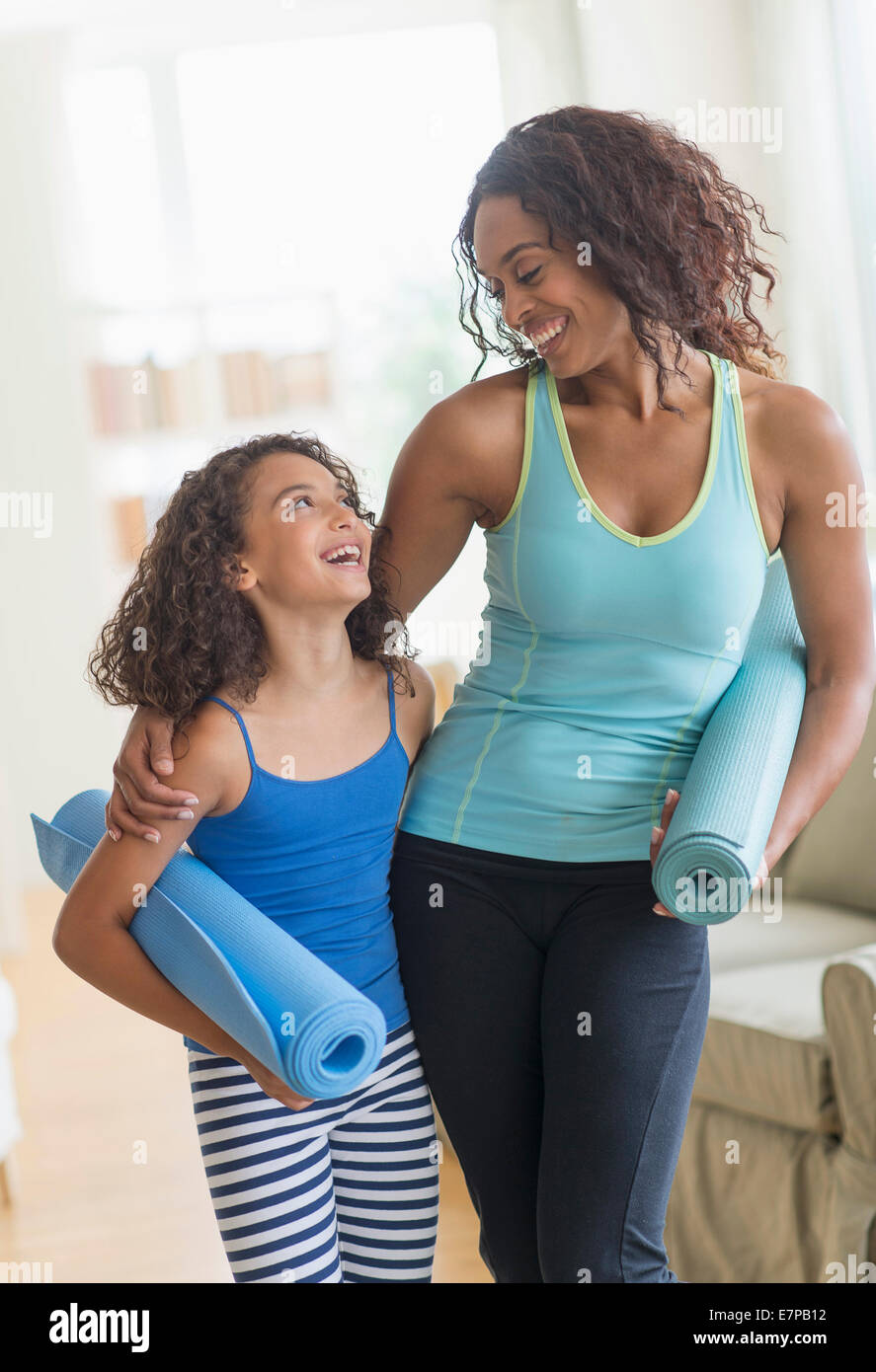 Mutter und Tochter (8-9) Holding Yoga Matten im Wohnzimmer Stockfoto