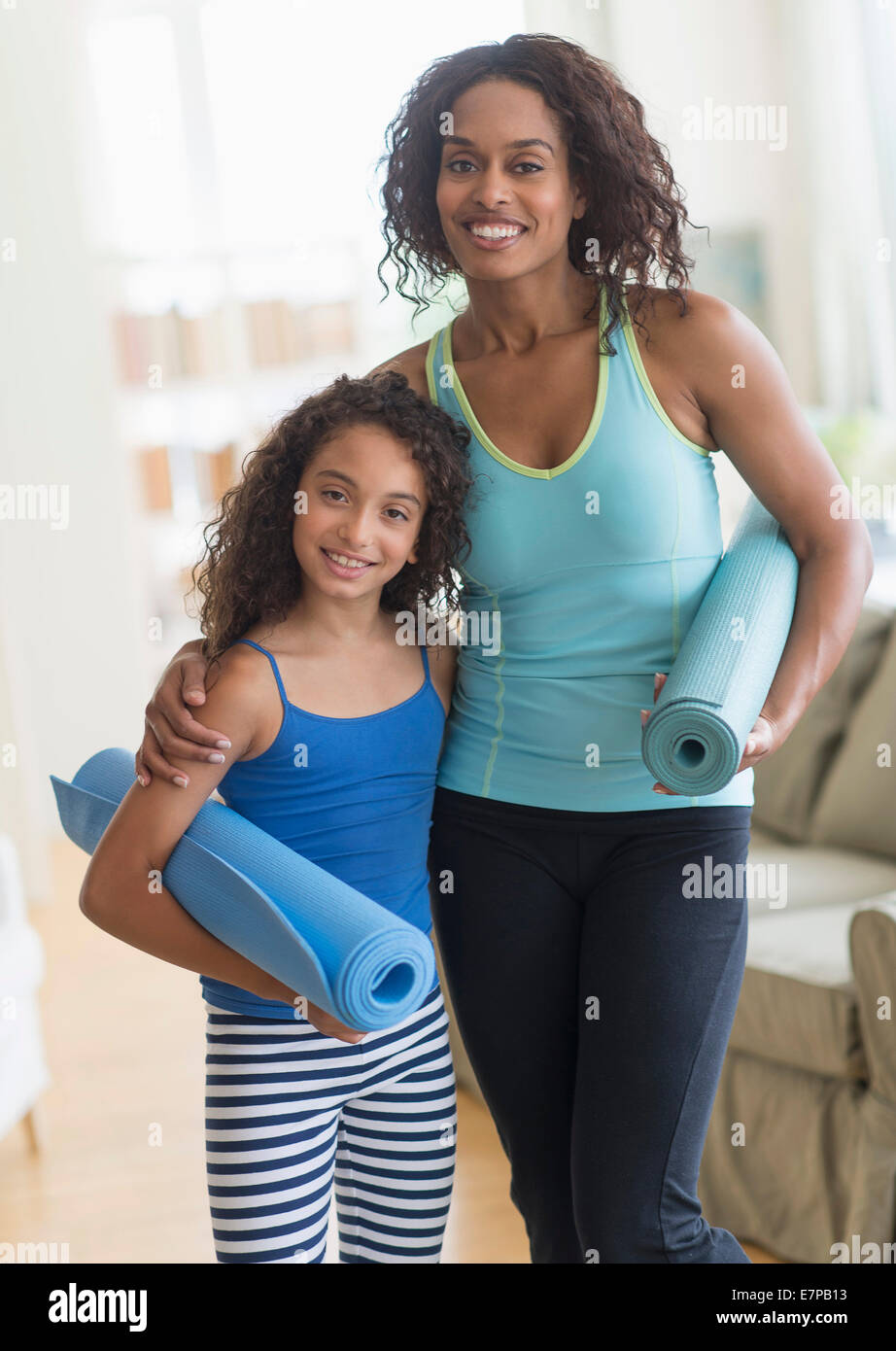 Mutter und Tochter (8-9) Holding Yoga Matten im Wohnzimmer Stockfoto