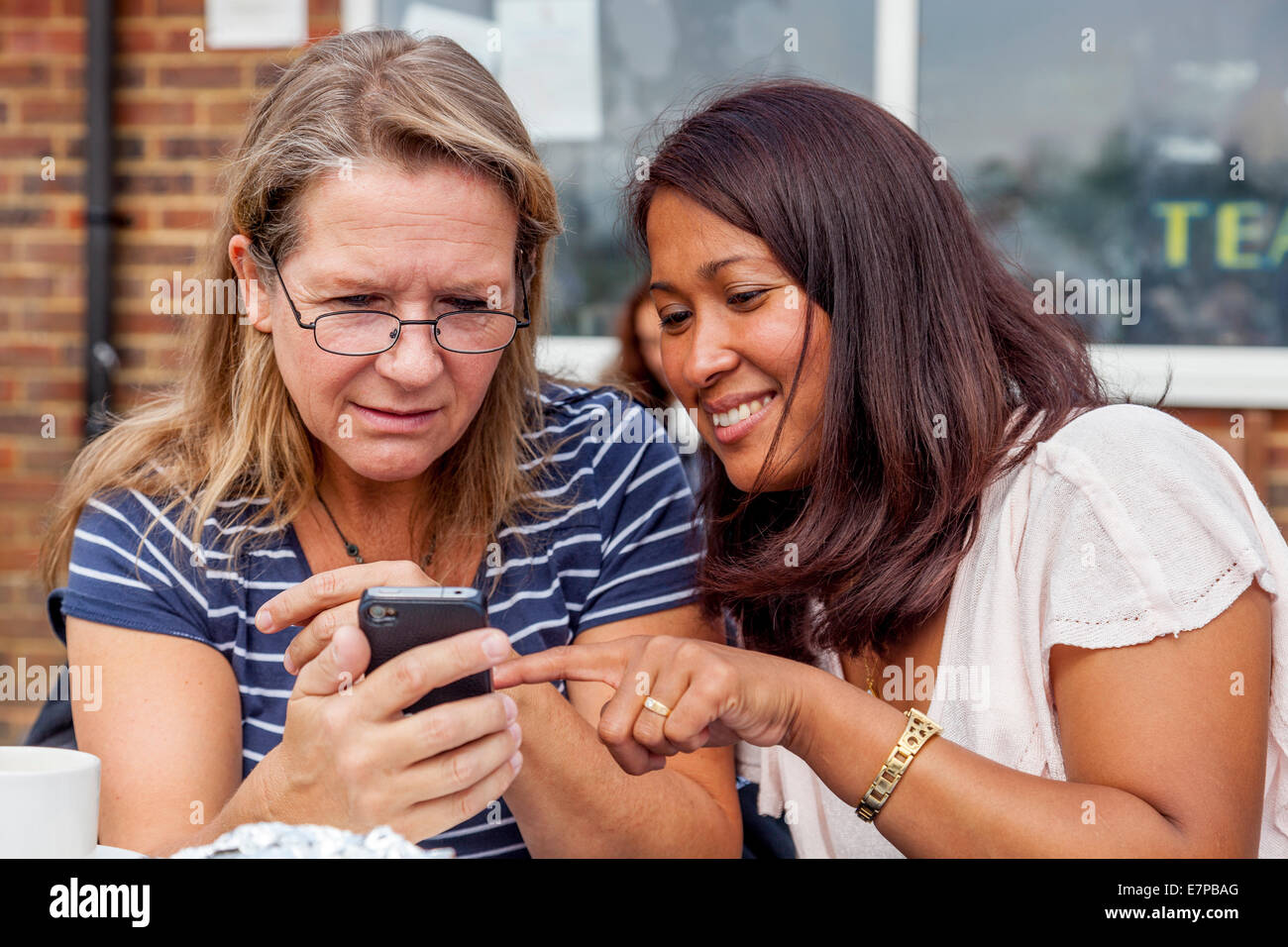 Zwei Frauen, die Fotos auf einem Smartphone, Hartfield Village Fete, Sussex, England Stockfoto