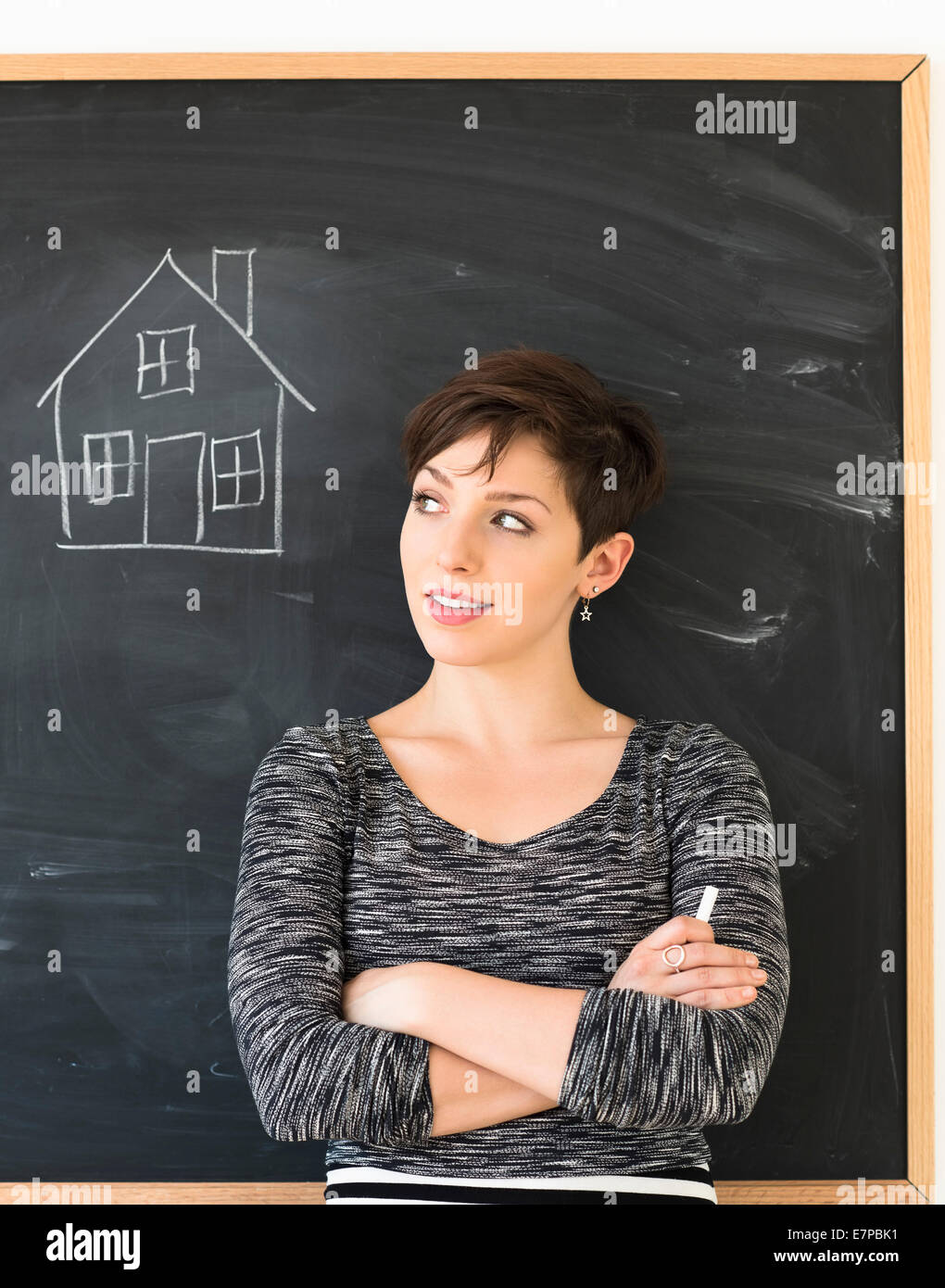 Frau vor Tafel mit Haus-Zeichnung Stockfoto