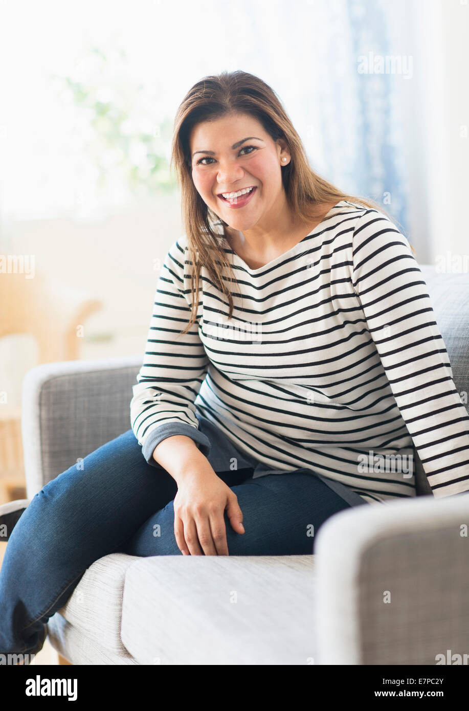 Porträt der glückliche Frau sitzend auf sofa Stockfoto