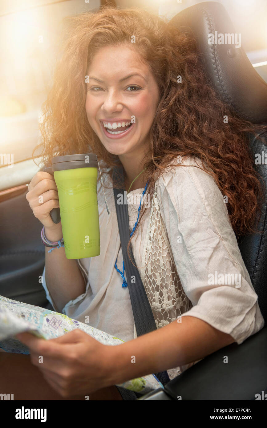 Frau sitzt im Auto mit Karte und Einweg-cup Stockfoto
