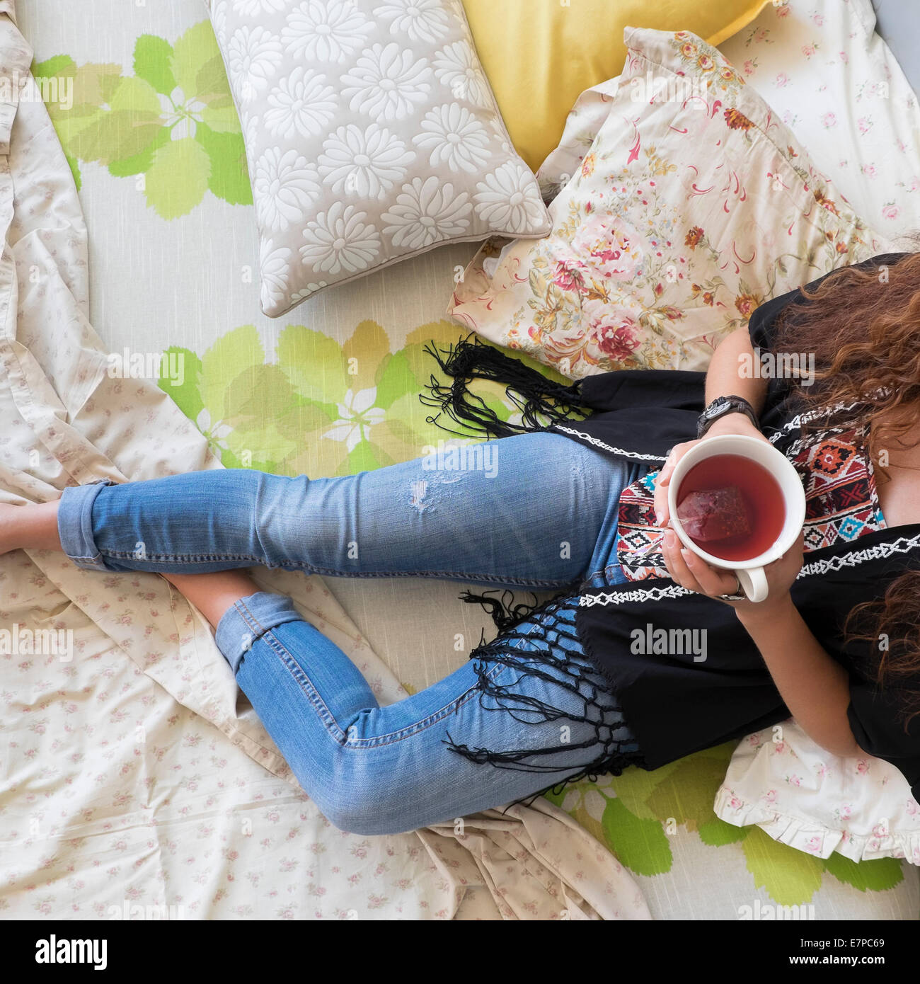 Frau liegend auf dem Bett mit Teetasse Stockfoto