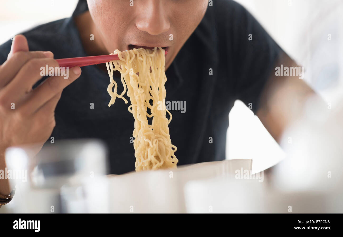 Mann isst Nudeln mit Stäbchen Stockfoto