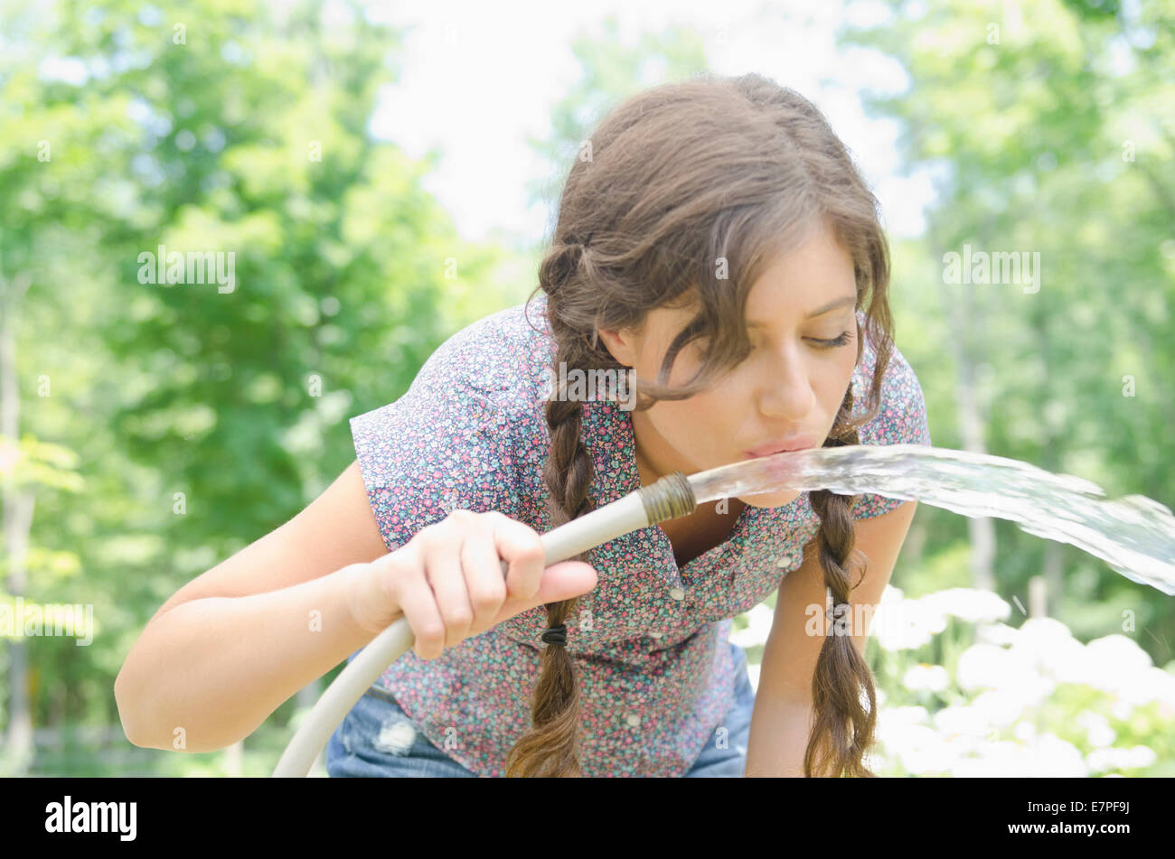 Frau Trinkwasser aus Gartenschlauch Stockfoto