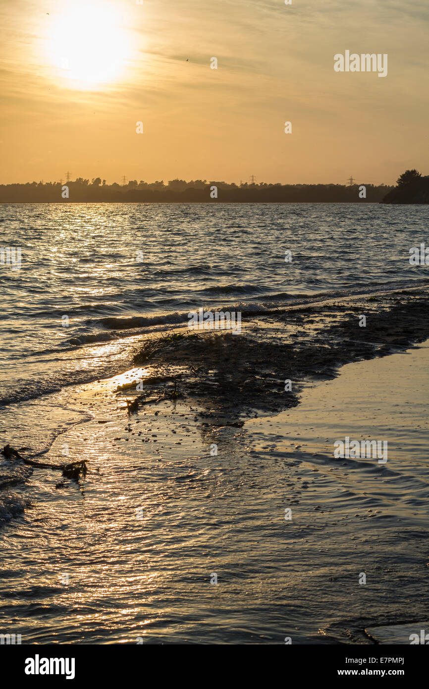 Tiefstehende Sonne mit warmen Schein mit Wasser plätschern am Ufer Stockfoto
