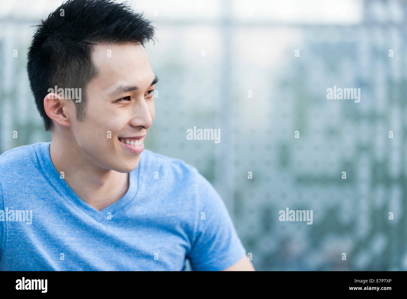 Porträt zuversichtlich jungen asiatischen Mannes im Profil, die lächelnd auf blauem Hintergrund mit Textfreiraum Stockfoto