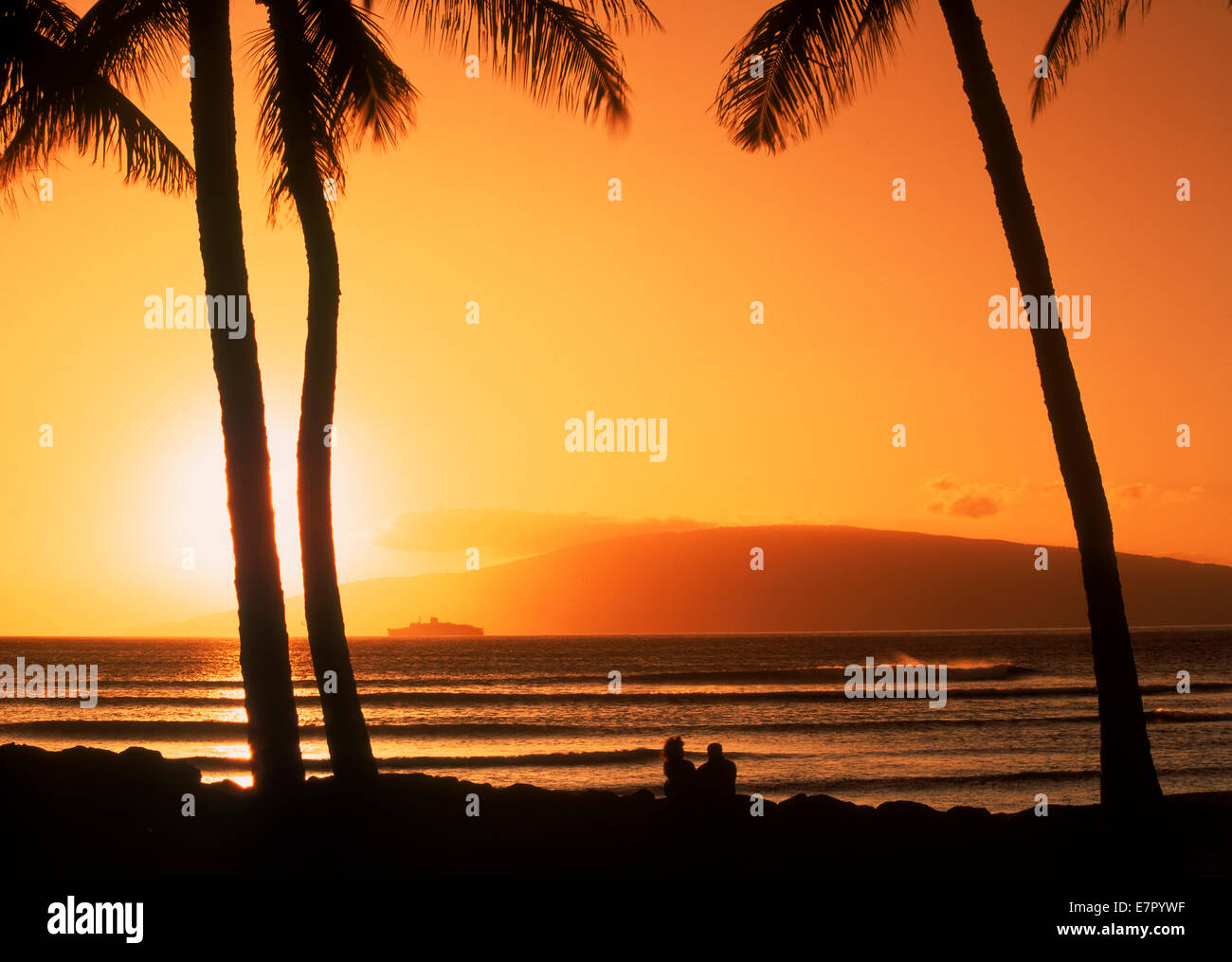 Paar unter Palmen auf Maui bei Sonnenuntergang mit Insel Lanai am Horizont Stockfoto