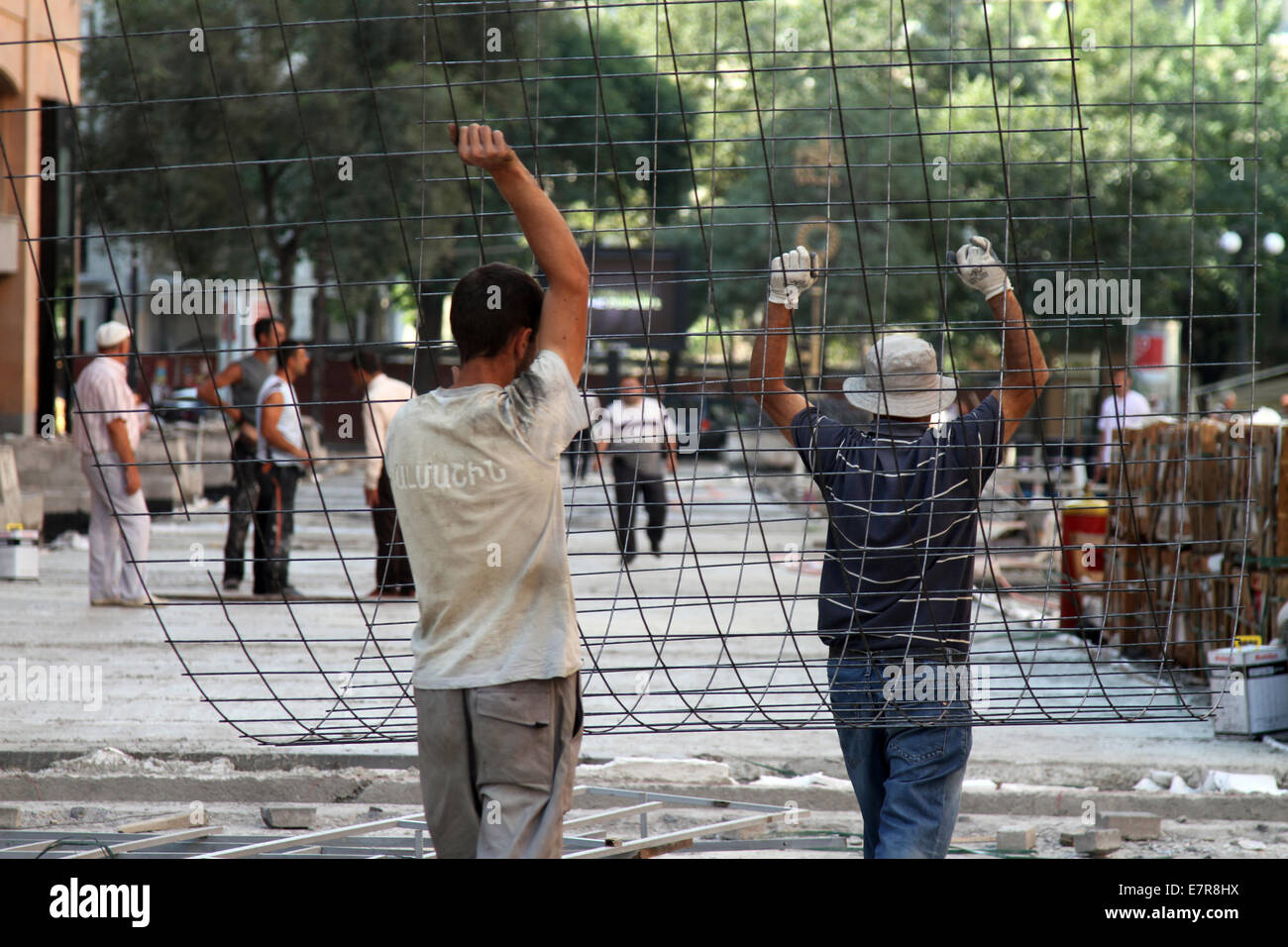 Arbeiter auf einer Baustelle an der Northern Avenue in zentralen Yerevan, Armenien, tragen Stahlnetz entlang der Straße. Stockfoto