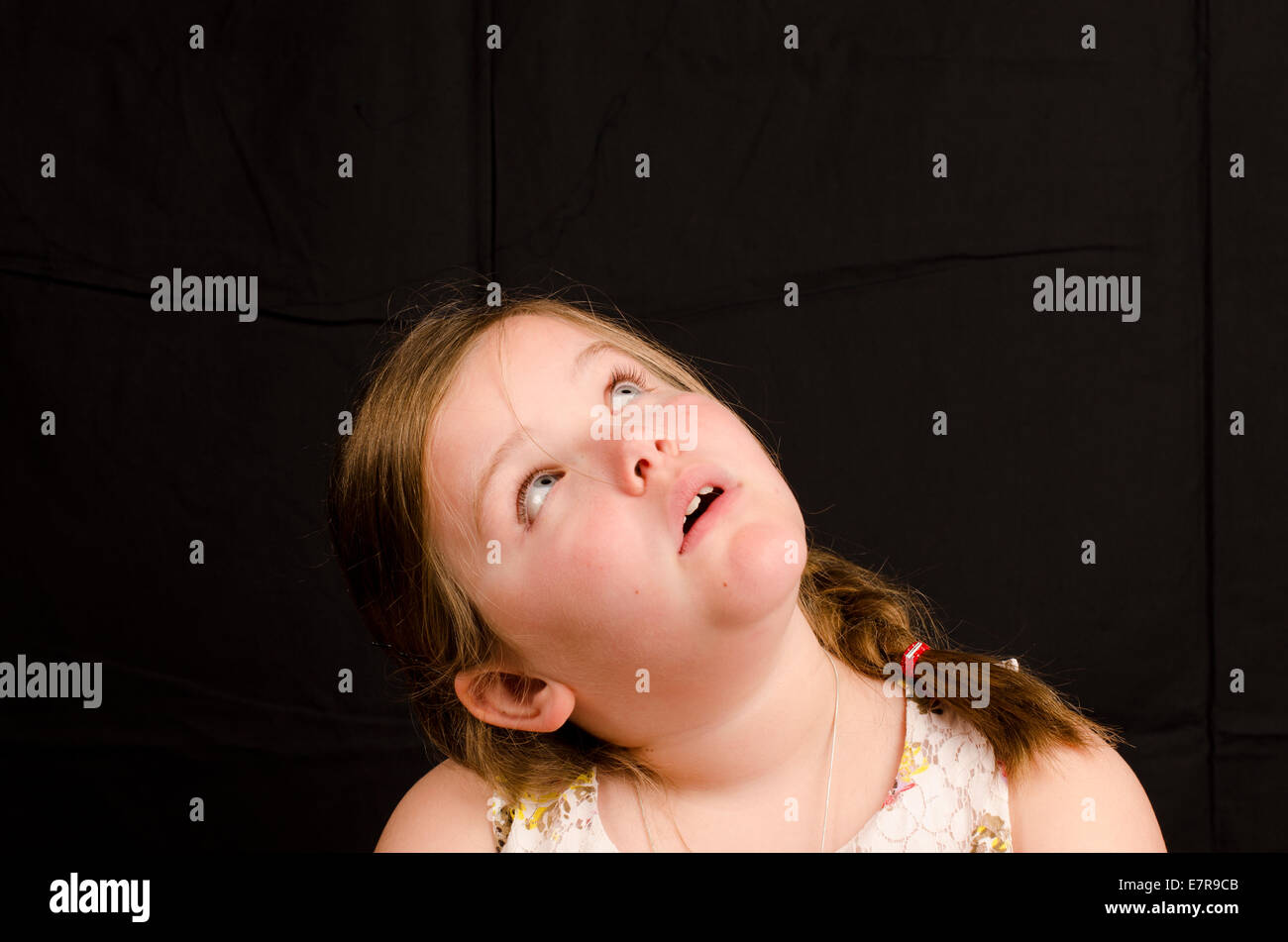 Bild von ein 8 Jahre altes Mädchen auf einem schwarzen Hintergrund blickt nach oben Stockfoto