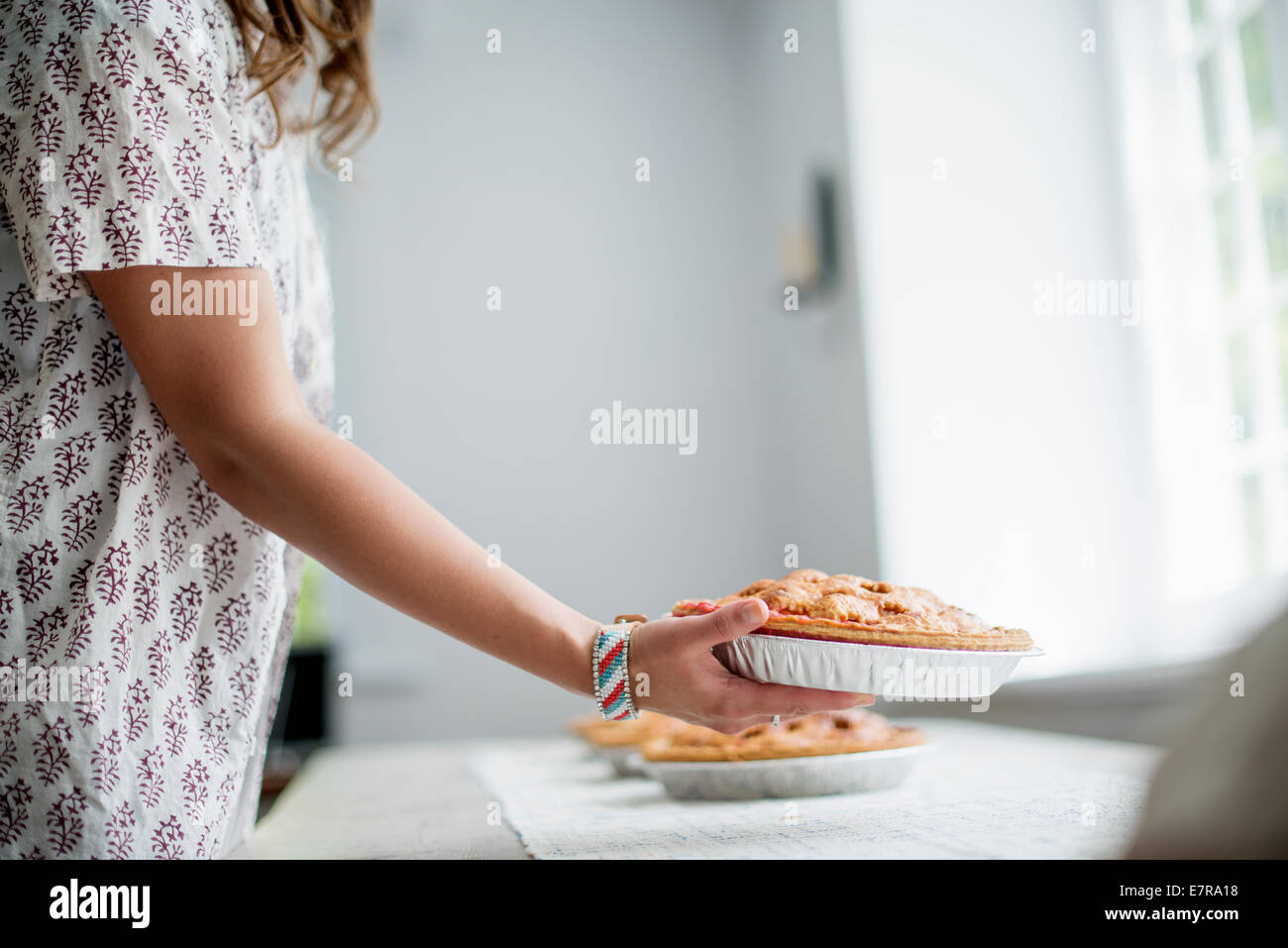 Eine Frau mit Nahrungsmitteln zu einer Tabelle für ein Familienessen vorbereiten. Stockfoto