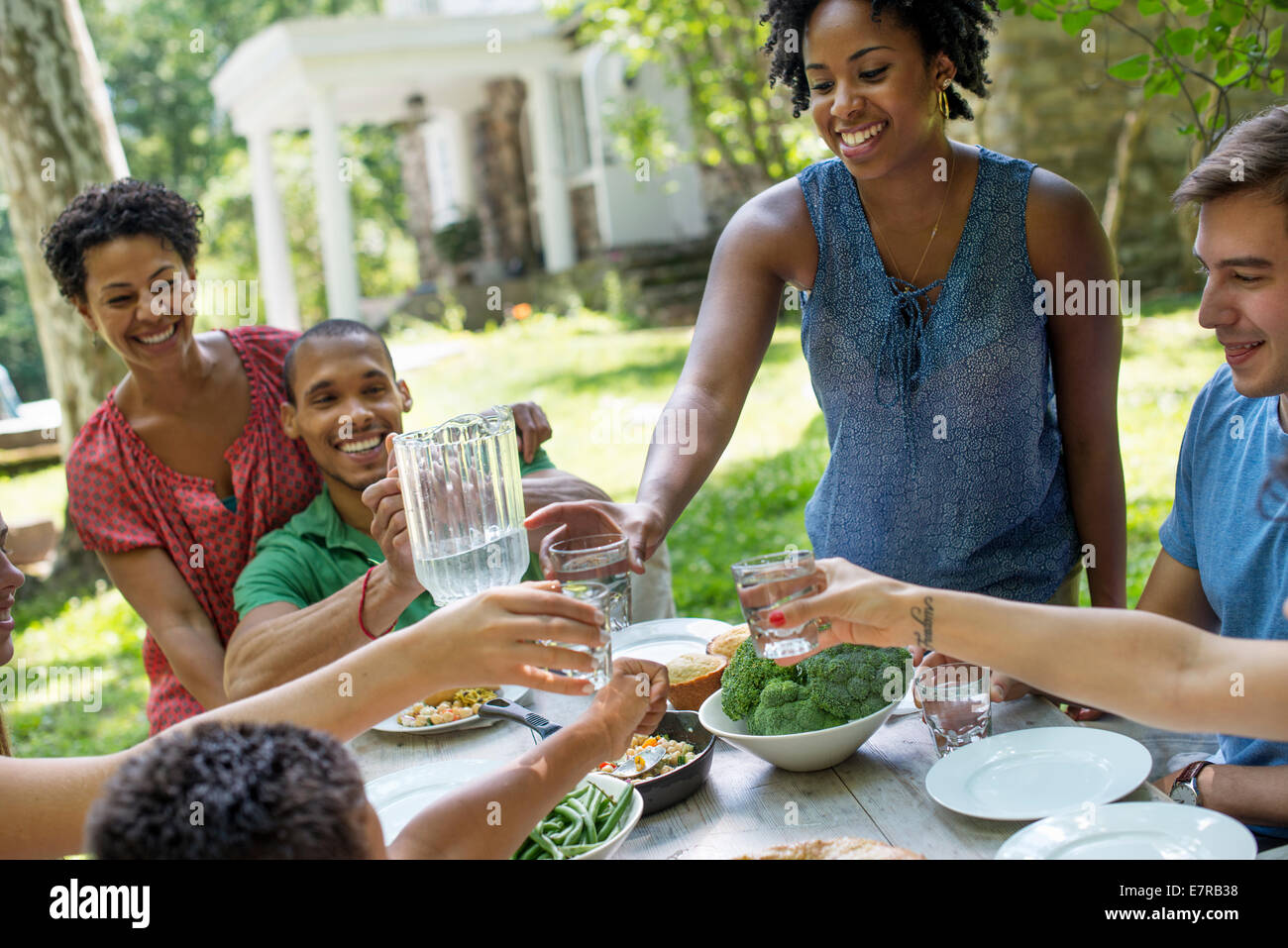 Ein Familientreffen, Männer, Frauen und Kinder an einem Tisch in einem Garten im Sommer. Stockfoto
