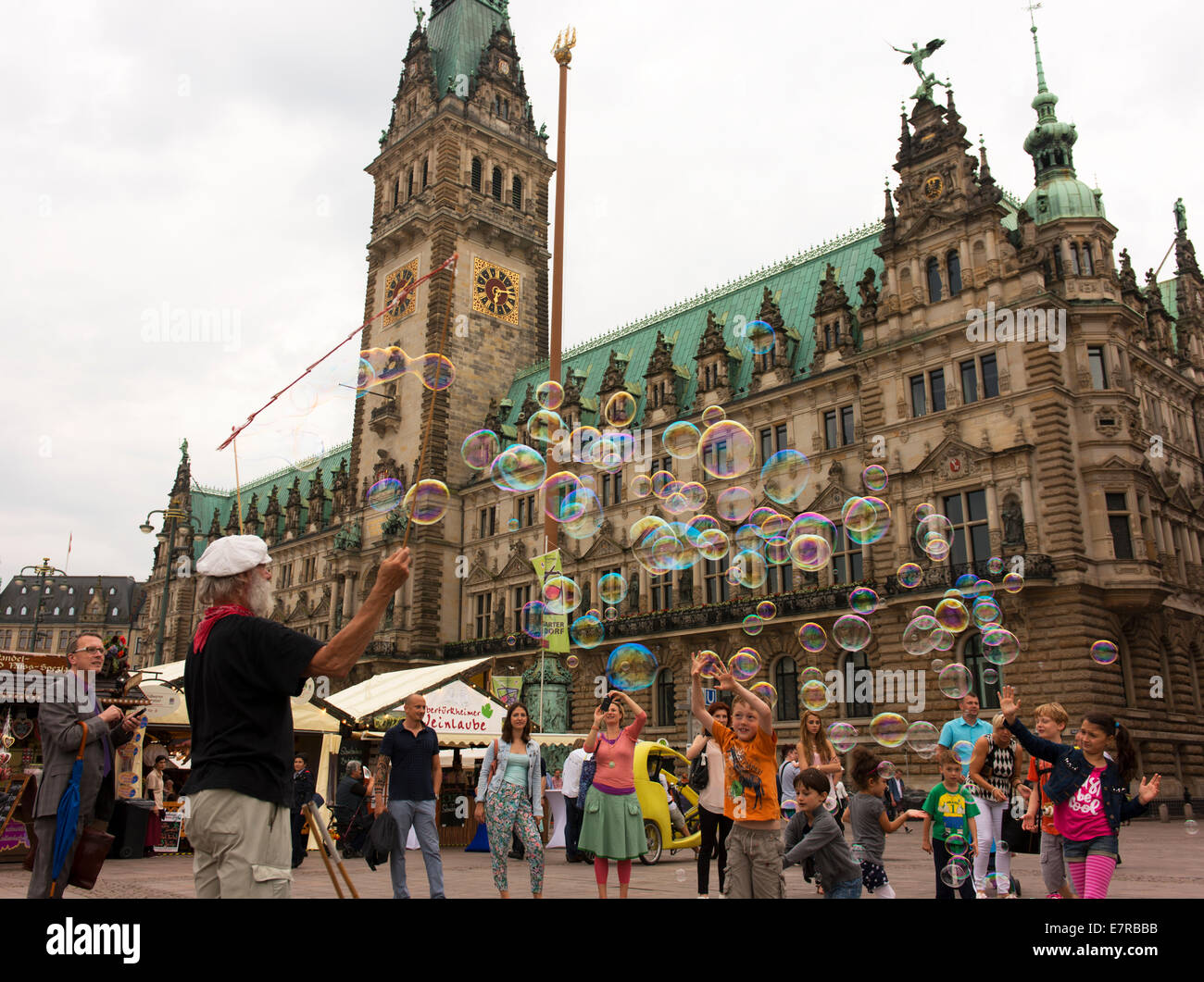 Kinder jagen und spielen mit Luftblasen in das Rathaus Marktplatz. Stockfoto