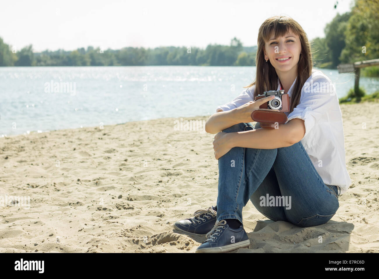 Lächelnde Hipster Frau posiert mit alten Film-Kamera am Strand im Sommer mittags. Urlaub-Hintergrund Stockfoto