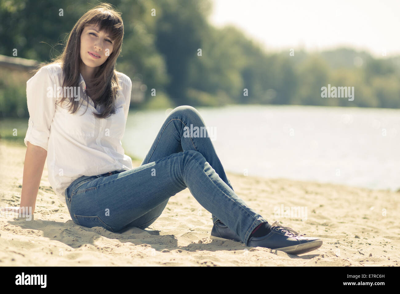 Junge hübsche Hipster Mädchen am Strand ausruhen. Kaukasische Frau sitzt auf Sand in der Nähe von Wasser. Stockfoto