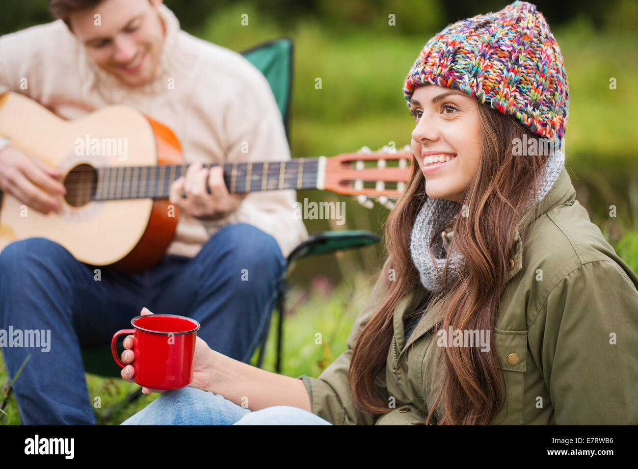 lächelnde paar mit Gitarre auf dem Campingplatz Stockfoto