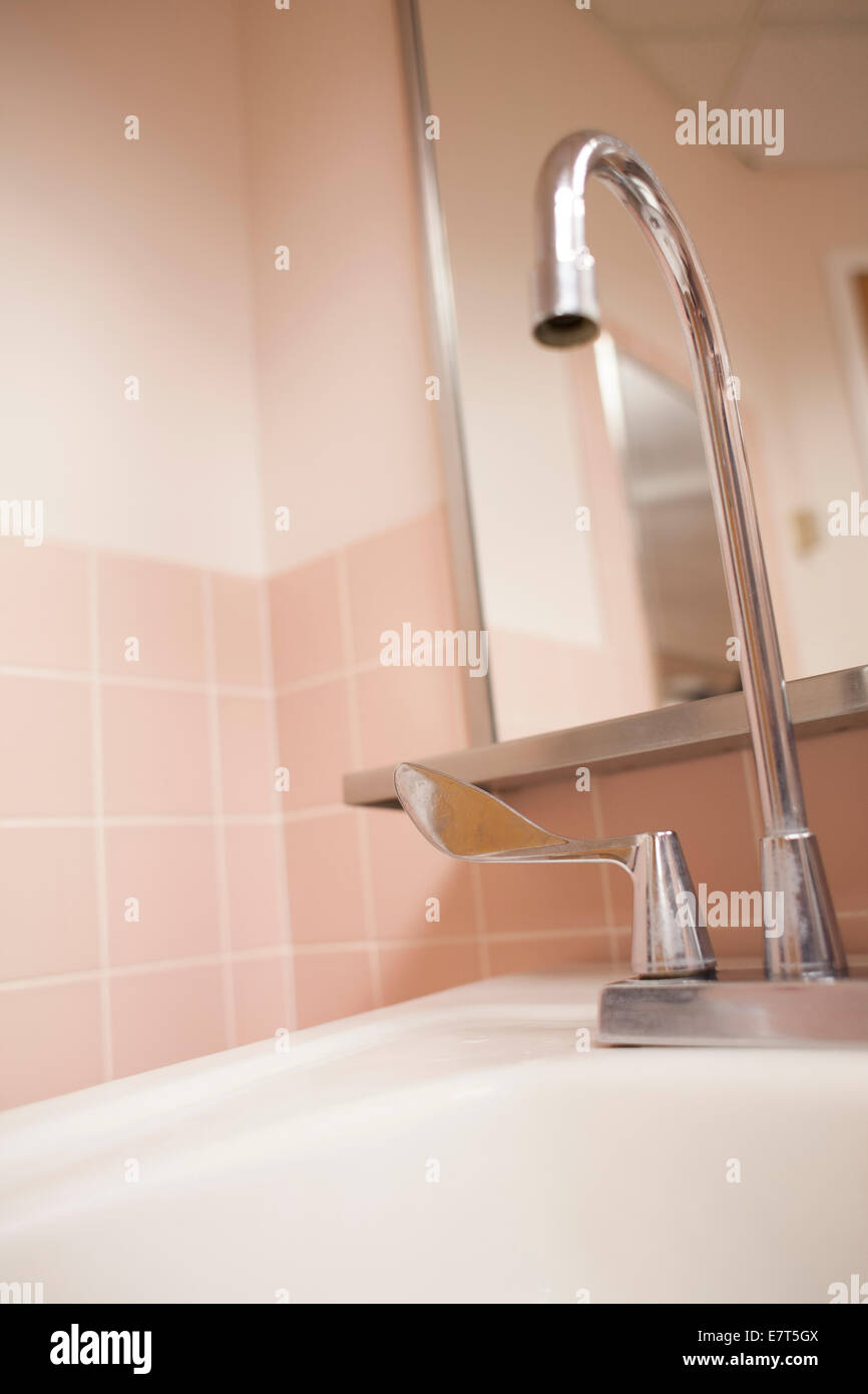 Waschbecken Sie in einem rosa gekachelten öffentlichen Bad in einem Krankenhaus. Stockfoto