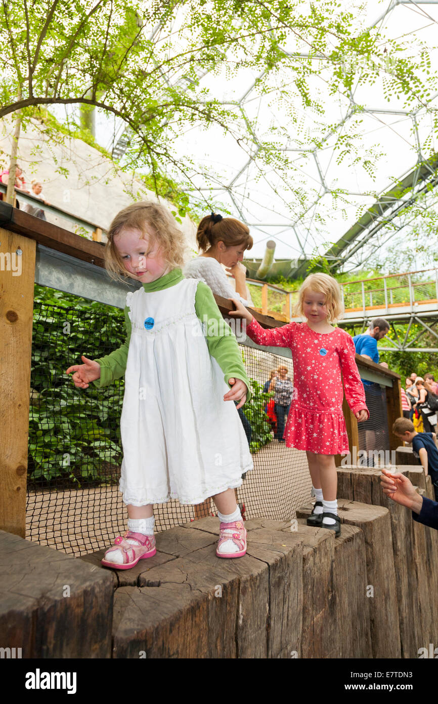 Ein zwei 2 Jahre altes Mädchen / Kind / Kinder / Kleinkinder und ihre vier 4 jährige Schwester zu Fuß / spielen in der Eden Projekt Biome. VEREINIGTES KÖNIGREICH. Stockfoto