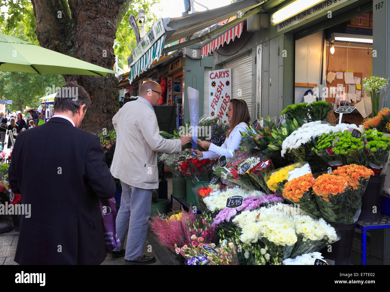 Ein Mann kauft Blumen an einem Stand an Norwich Markt, England. Stockfoto